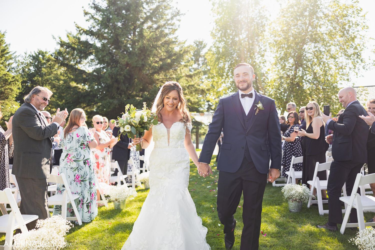 Happy couple exits wedding ceremony while guests cheer and celebrate.