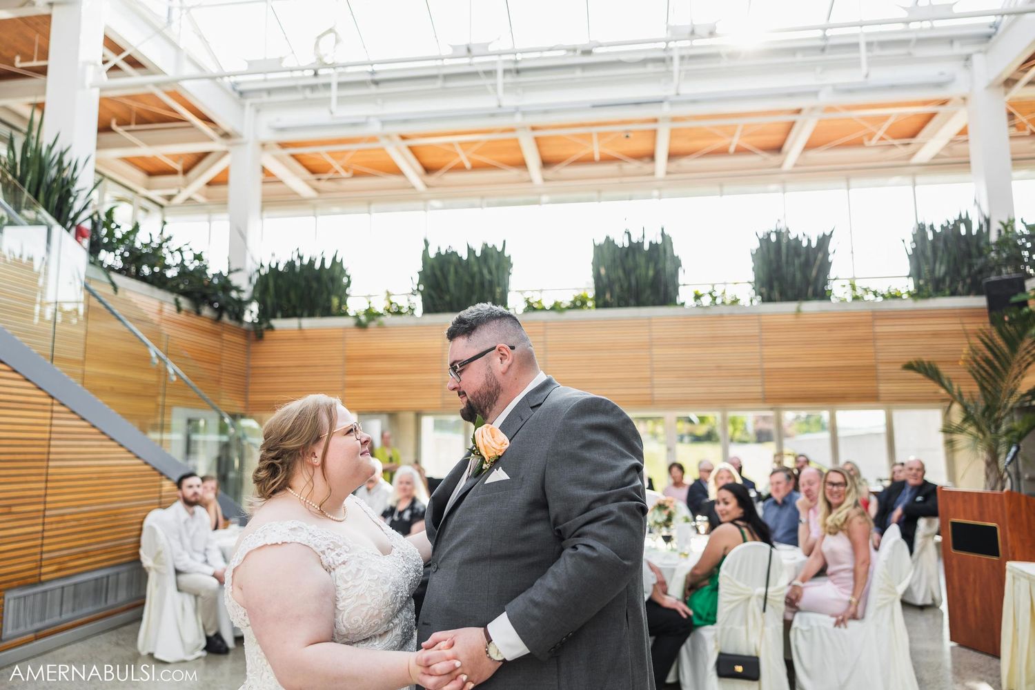 A couple dances and smiles at each other during their wedding reception in a modern venue.
