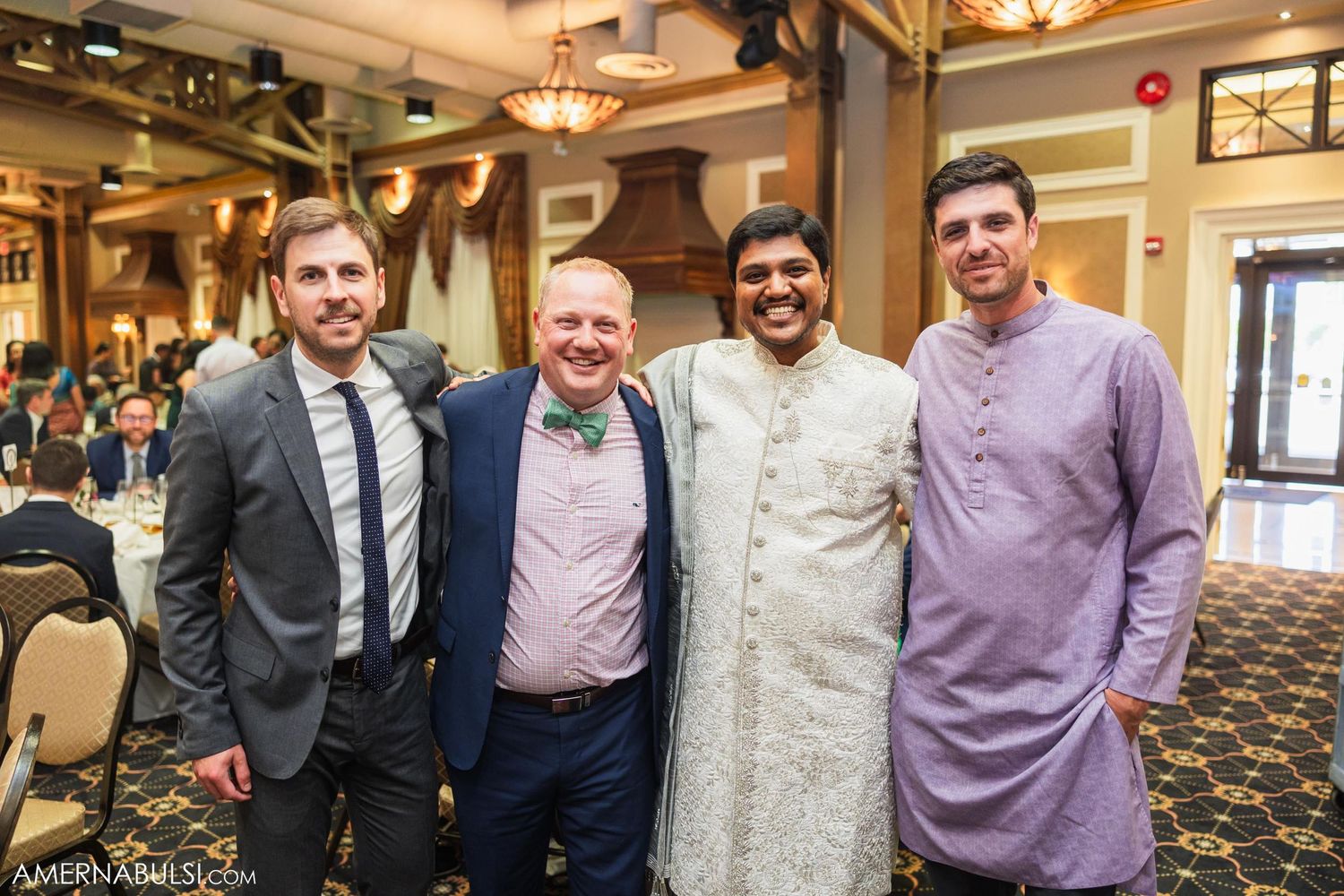 A group of formally dressed guests gather for a photo at a wedding reception.