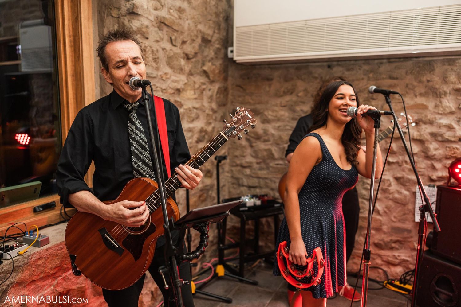 Musicians performing with guitar and vocals at rustic wedding reception venue.
