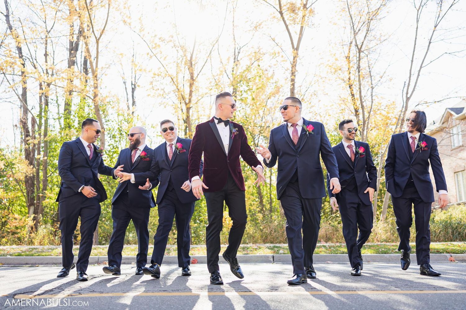 Wedding party in formal attire walking and jumping on outdoor path.