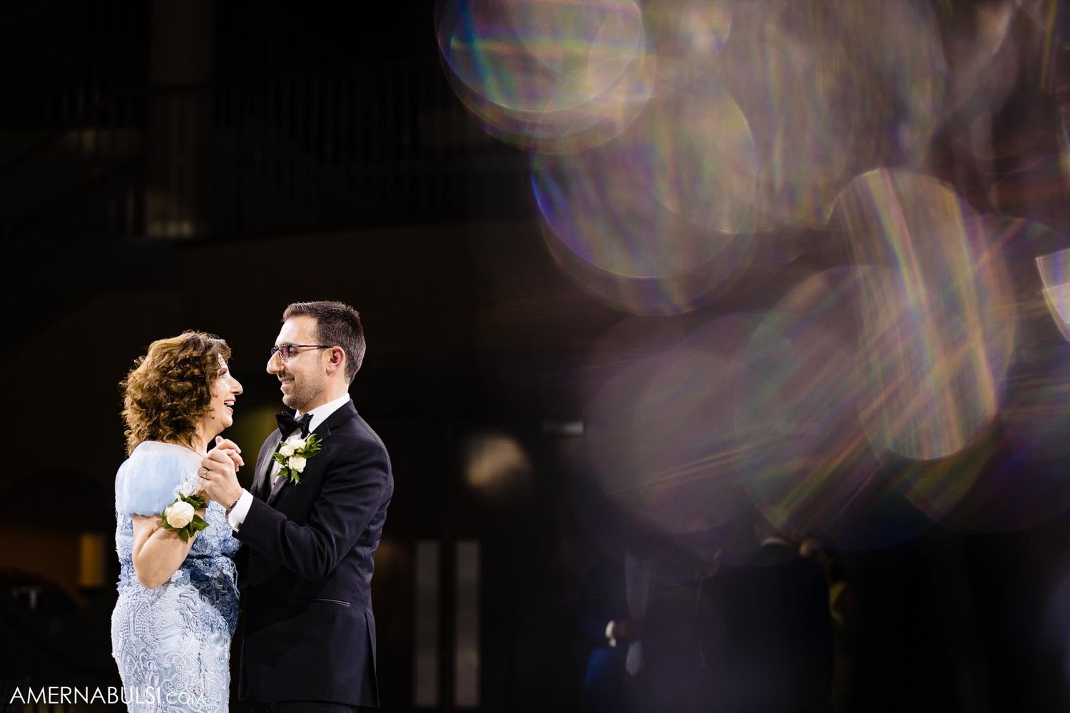 A couple shares an intimate dance moment with beautiful lens flare effects in the background.