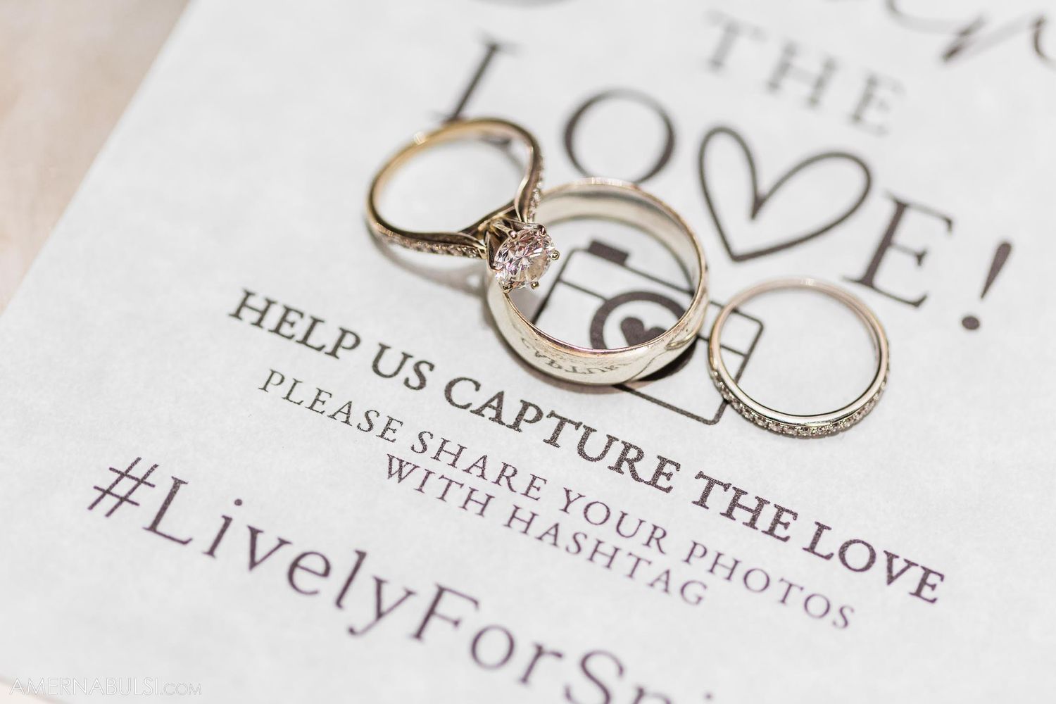 Wedding rings arranged creatively on invitation with hashtag detail.