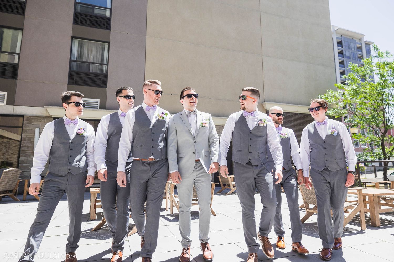Group of groomsmen in matching gray suits and vests posing outdoors.