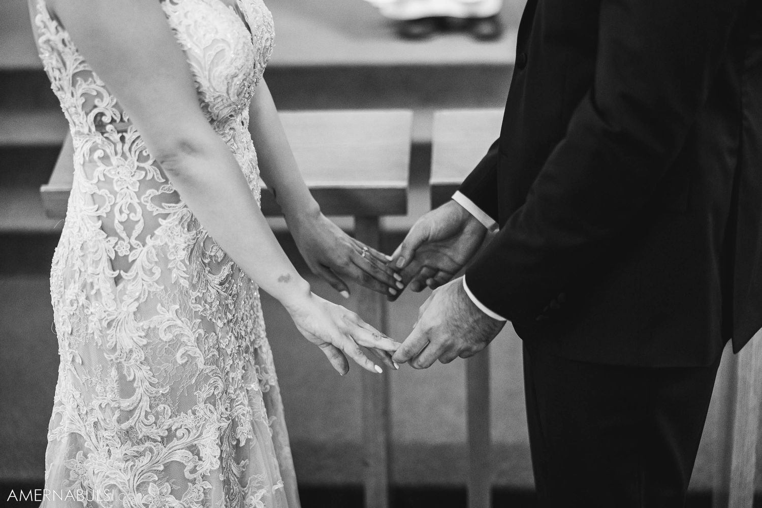 A black and white close-up photo of hands exchanging rings during a wedding ceremony.