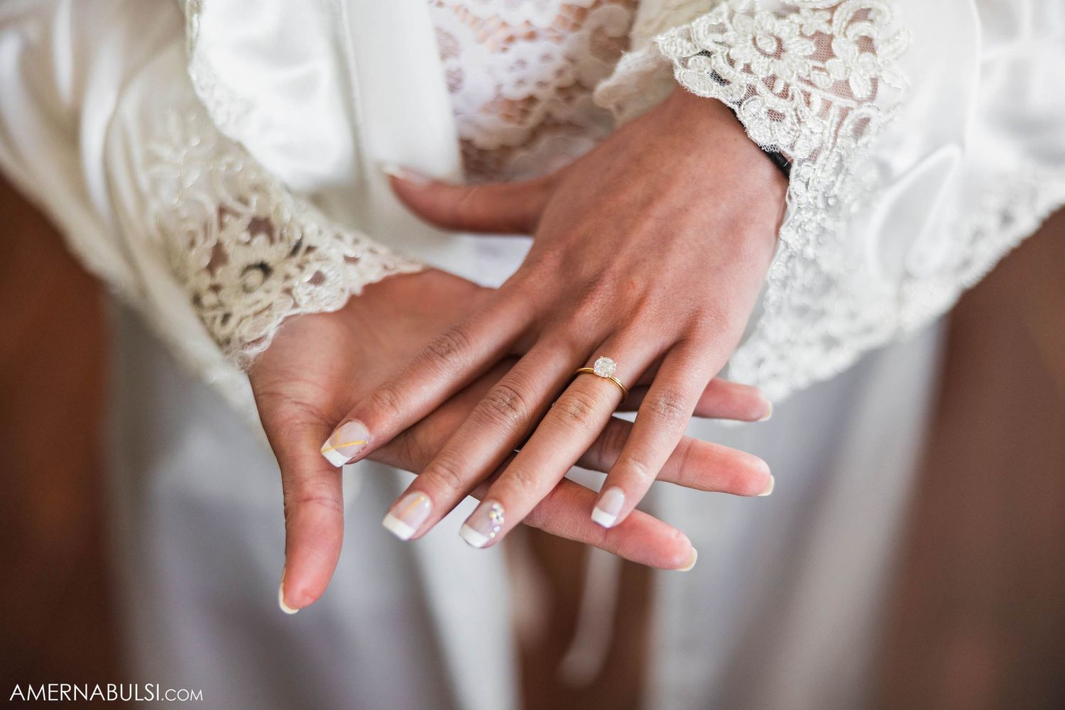Close-up of bride's hands showing off wedding ring and lace sleeve details.