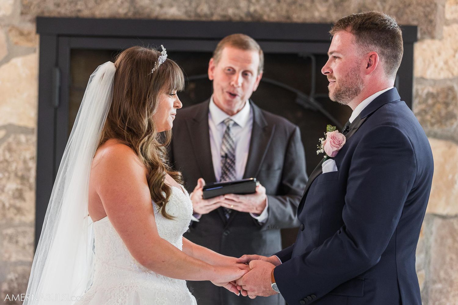 Exchange of vows during intimate wedding ceremony in front of stone fireplace.