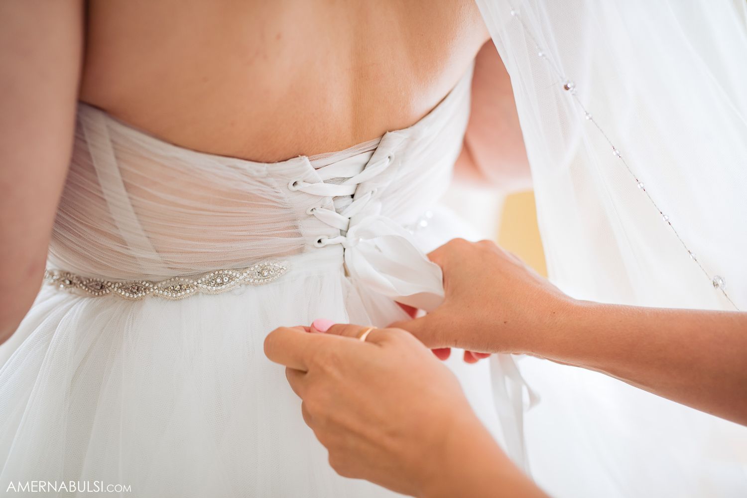 Close-up details of white wedding dress showing intricate beading and fabric textures.