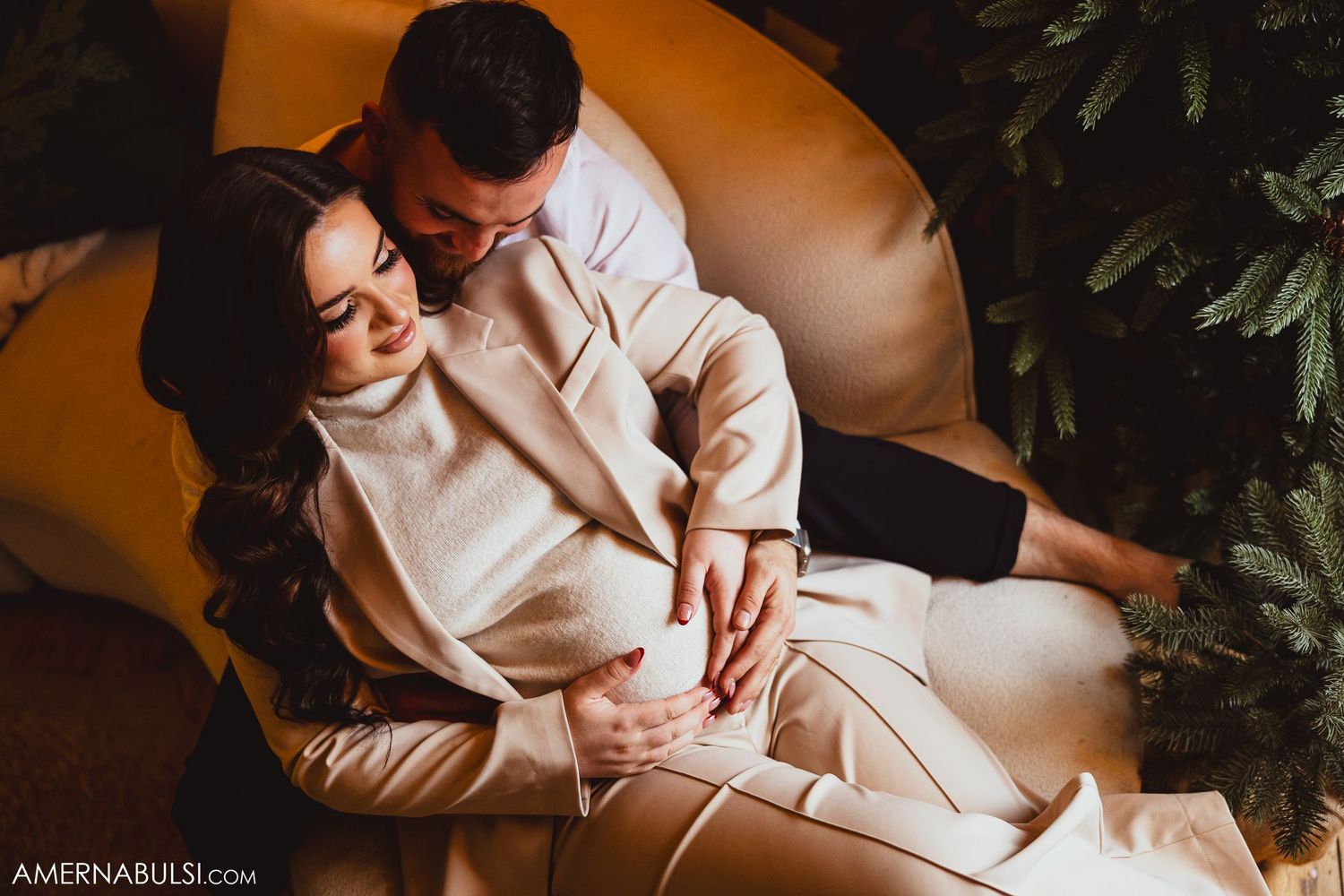 mom and dad sitting on a couch touching the baby bump