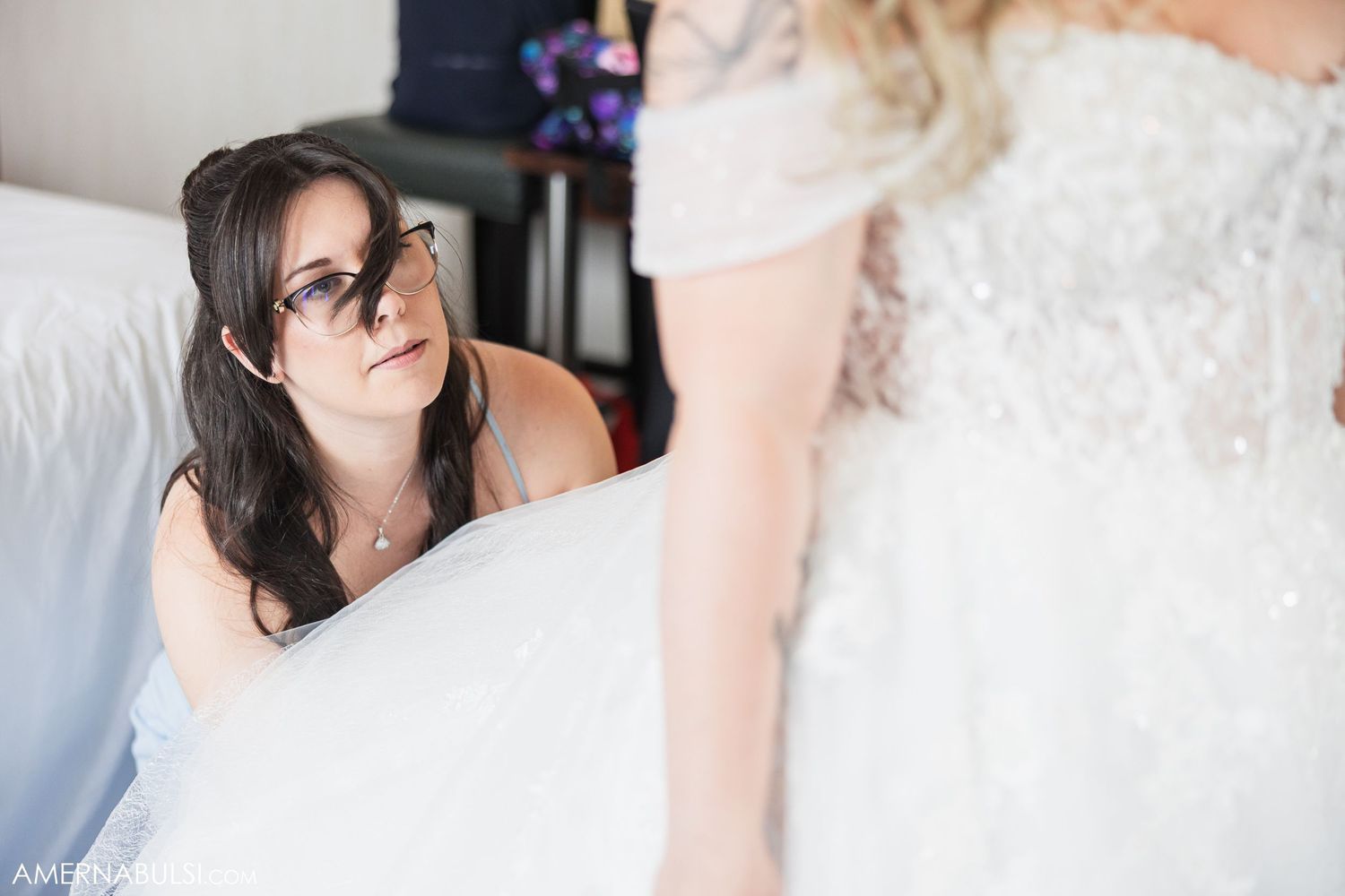 Close-up details of delicate white lace wedding dress in natural lighting.