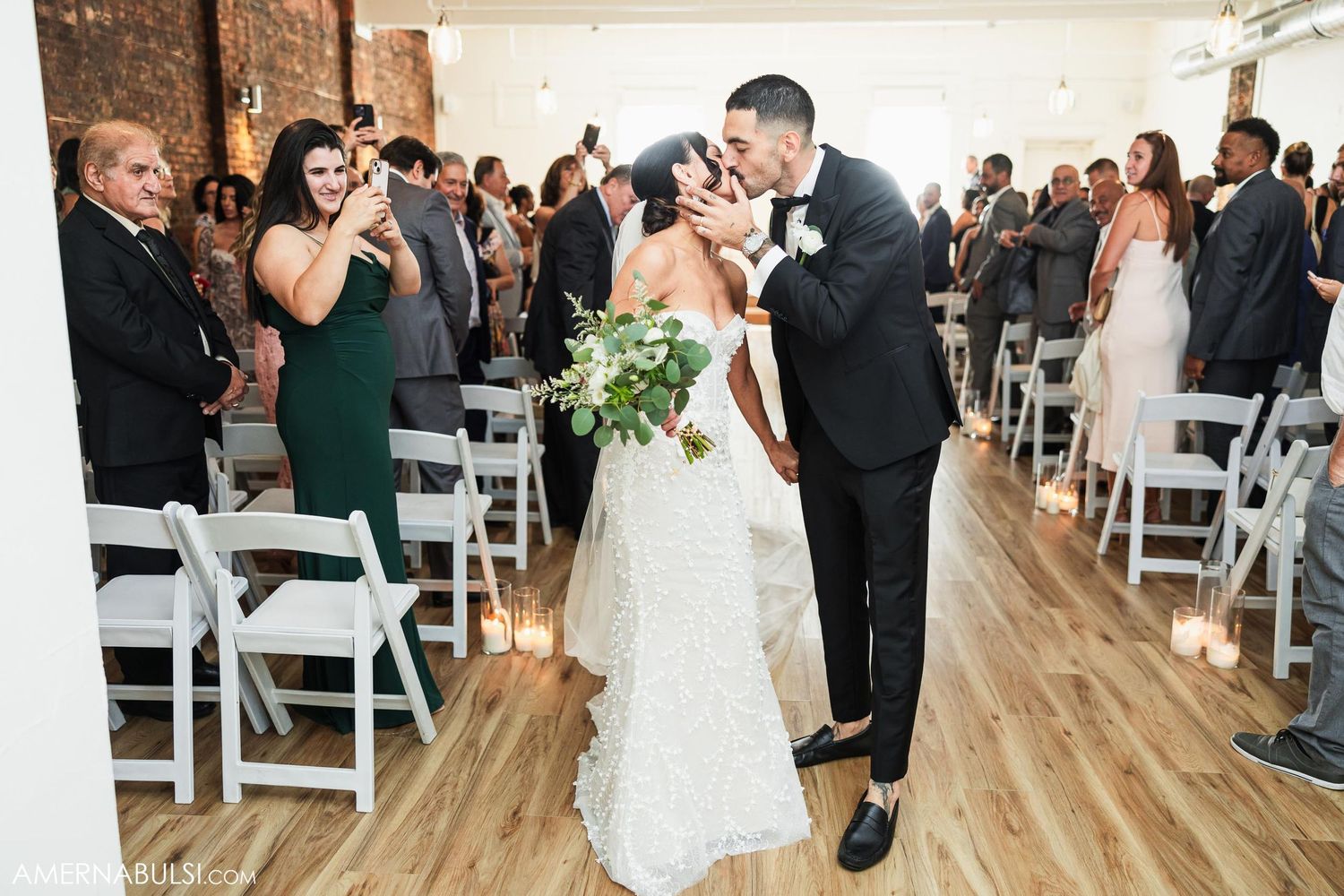 Wedding couple shares a celebratory moment in an aisle lined with white chairs.