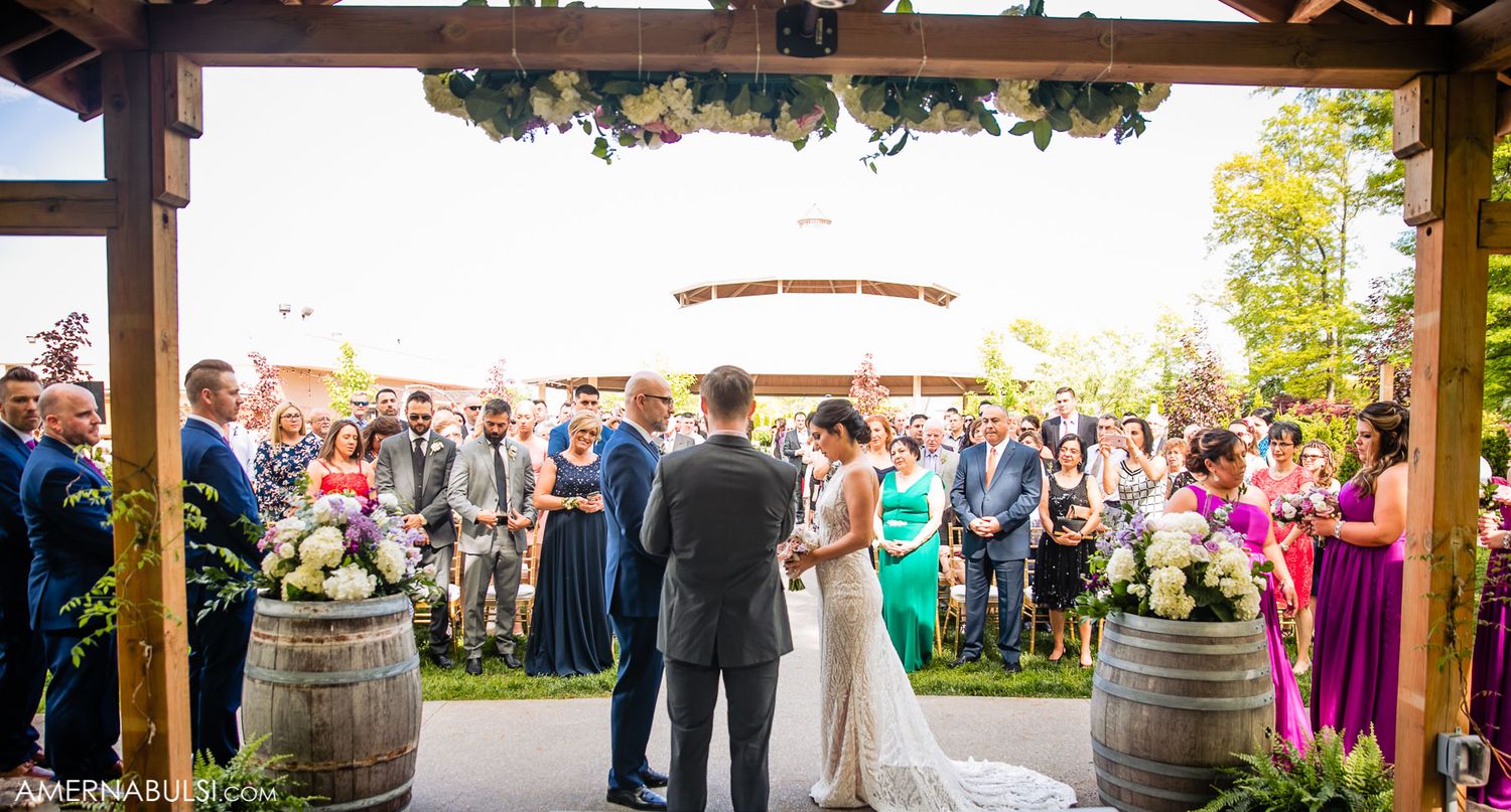 Panoramic view of wedding guests mingling under a covered outdoor pavilion.
