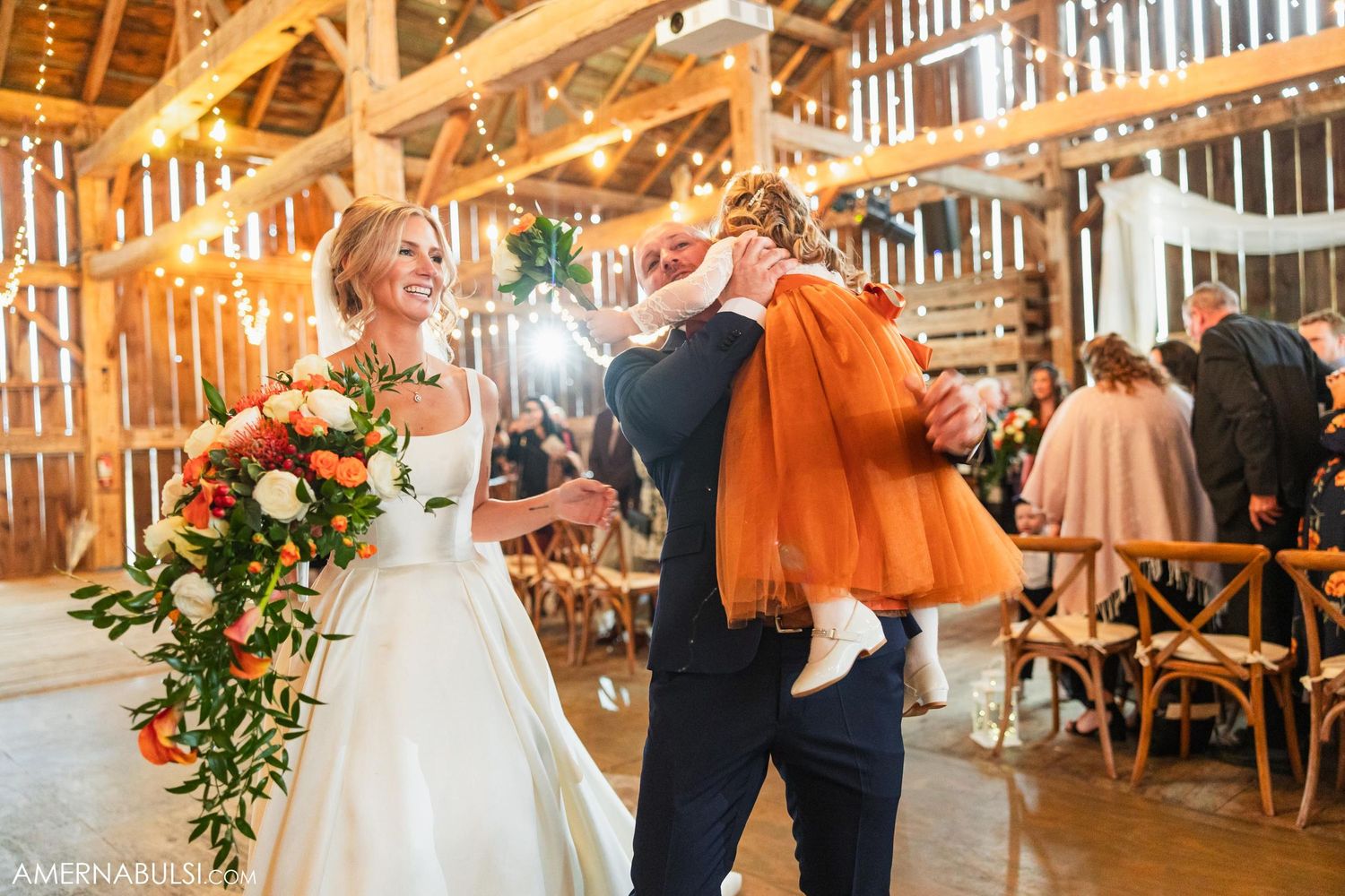Dancing couple celebrates in rustic barn venue with warm lighting and wooden beams.