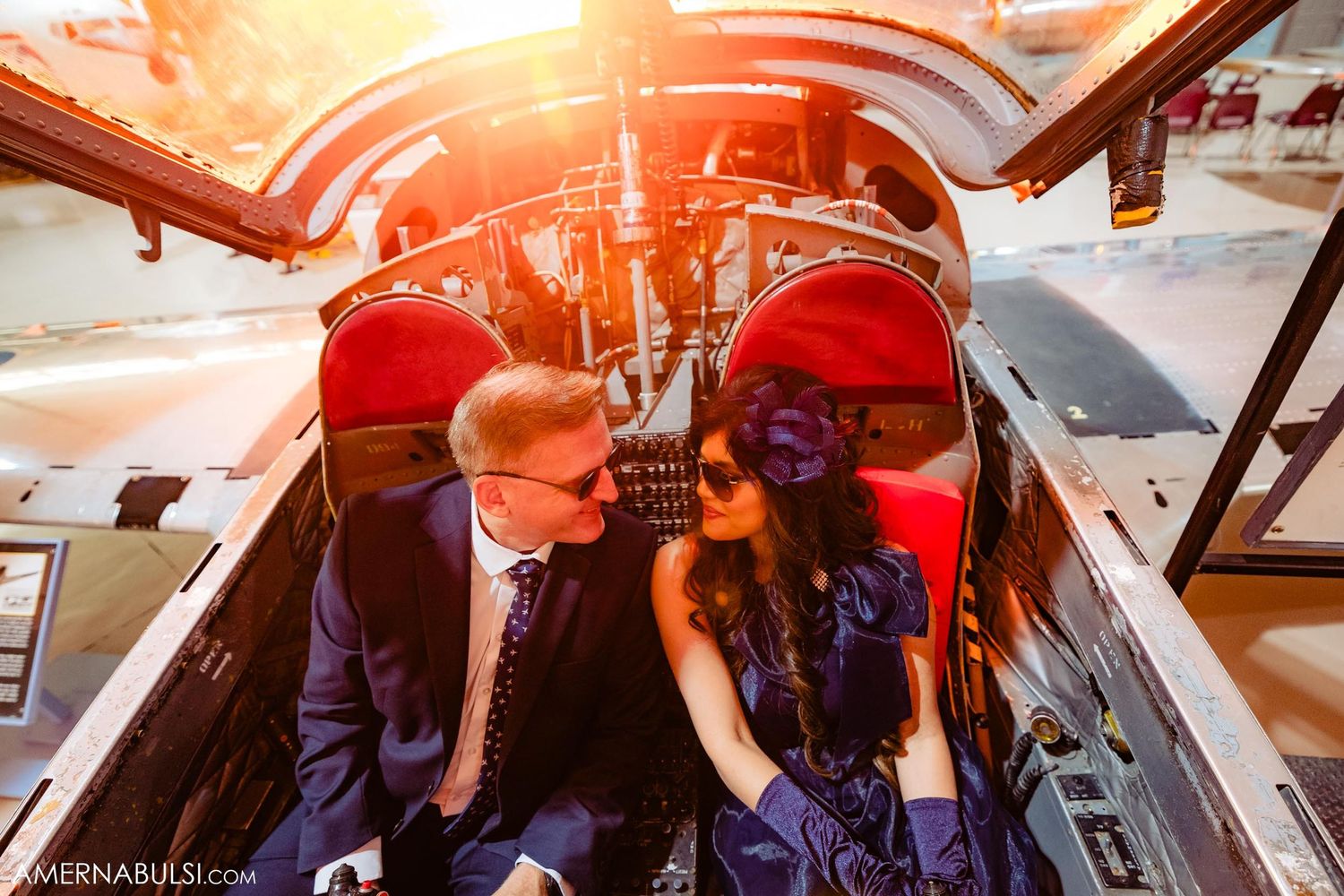 Couple posing inside vintage aircraft cockpit during sunset photoshoot.