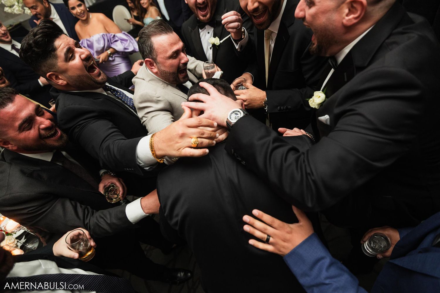 A chaotic celebratory moment at a wedding reception with people reaching and laughing in excitement.