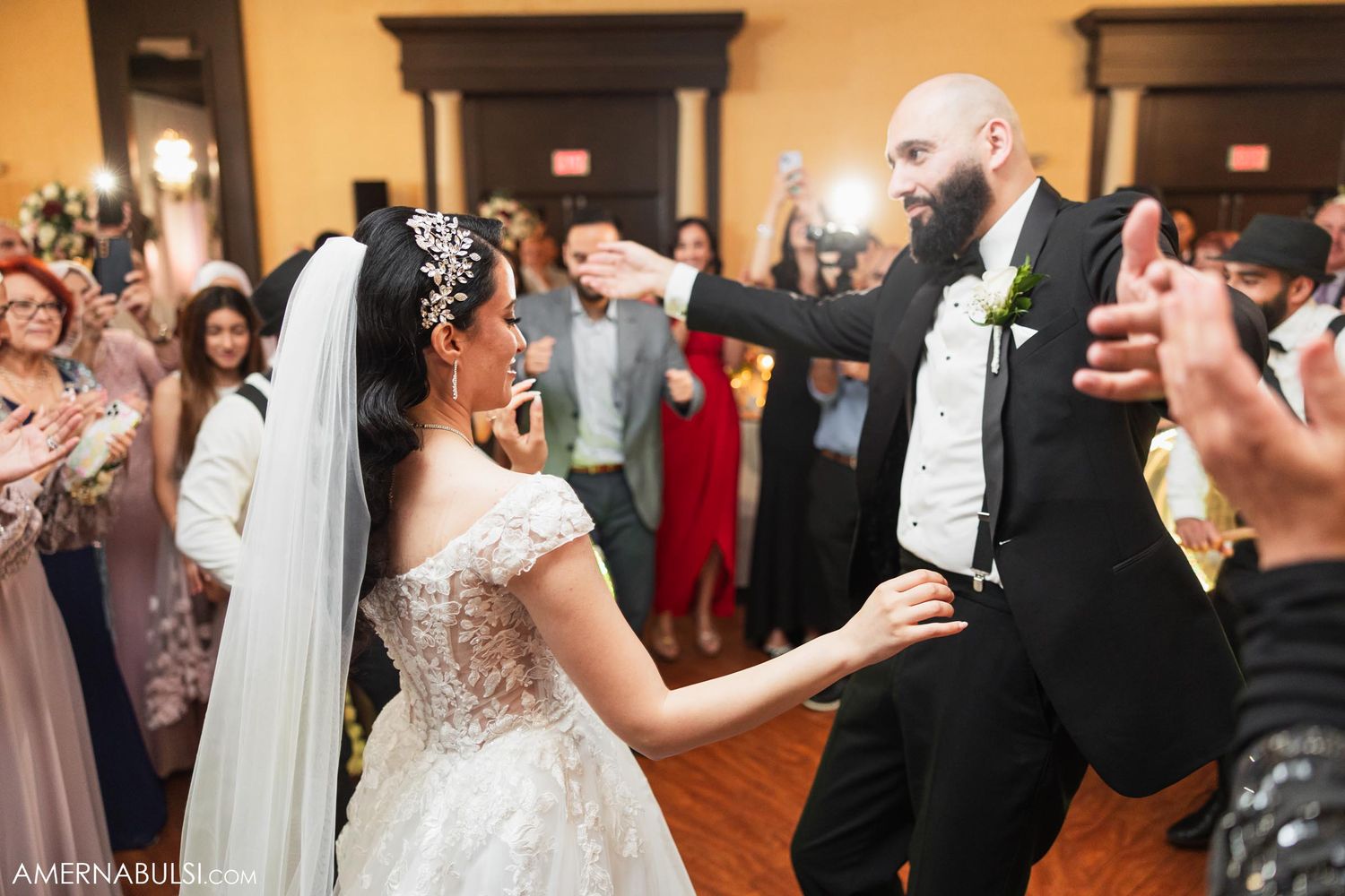 A couple dancing together during their wedding reception while guests cheer them on.