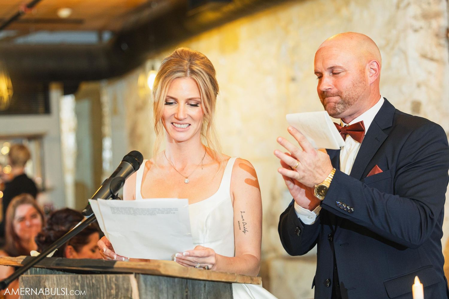 Two people giving speeches at a formal wedding reception with paper notes and a microphone.