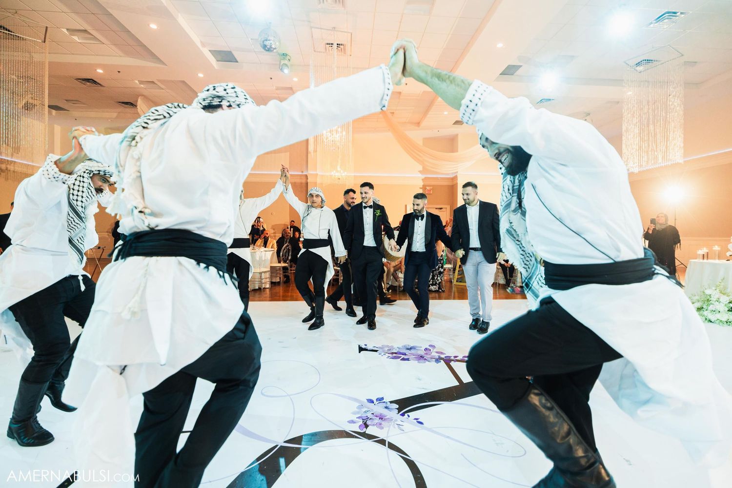 Traditional dancers perform in white martial arts uniforms at a wedding reception.