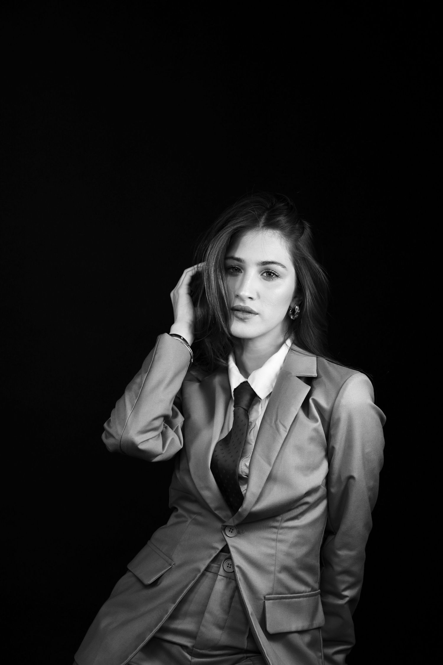 Elegant woman in suit and tie with long hair in black and white portrait.