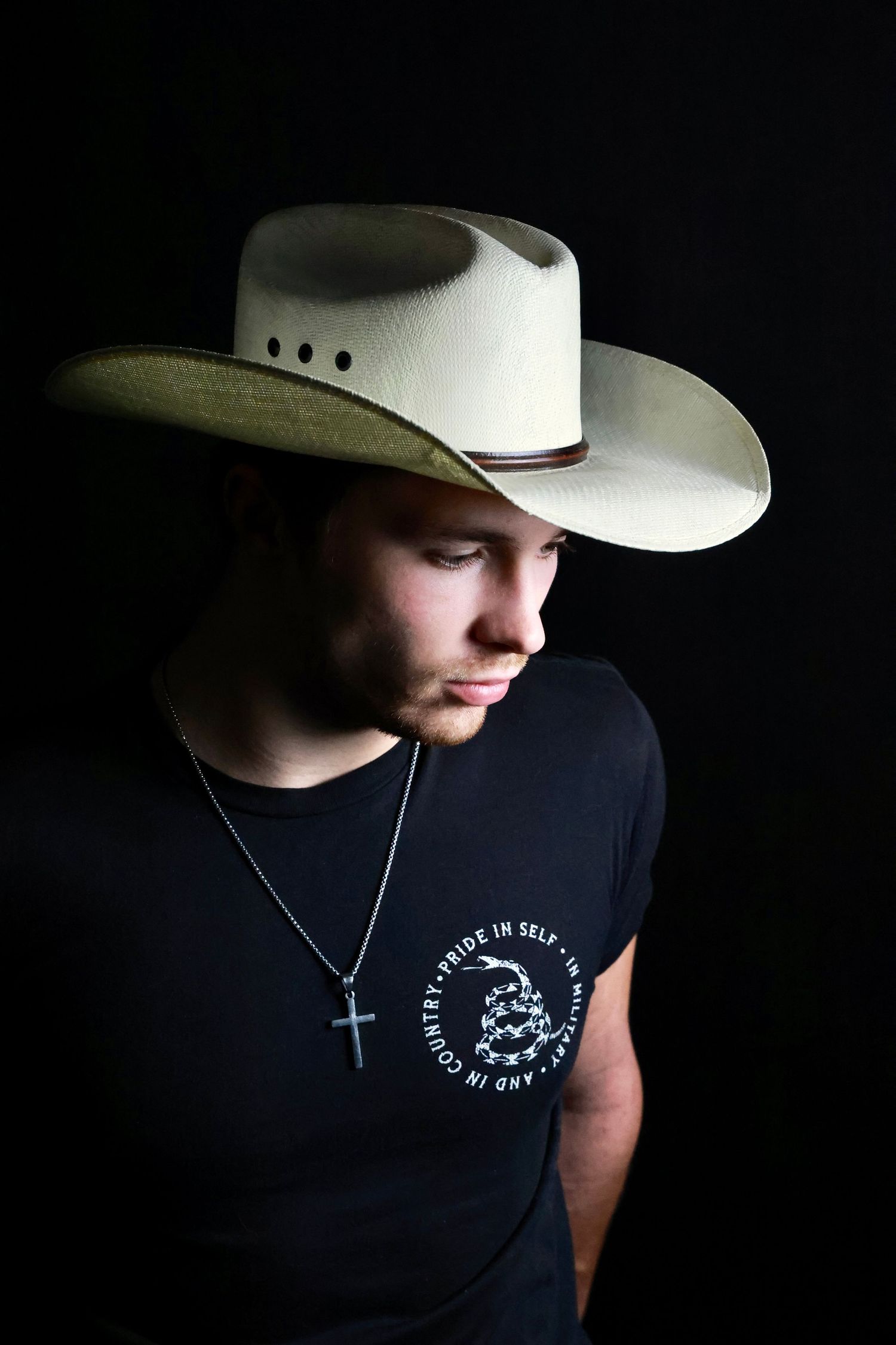 A series of dark moody portraits showing someone wearing a white cowboy hat and black t-shirt against a black background.