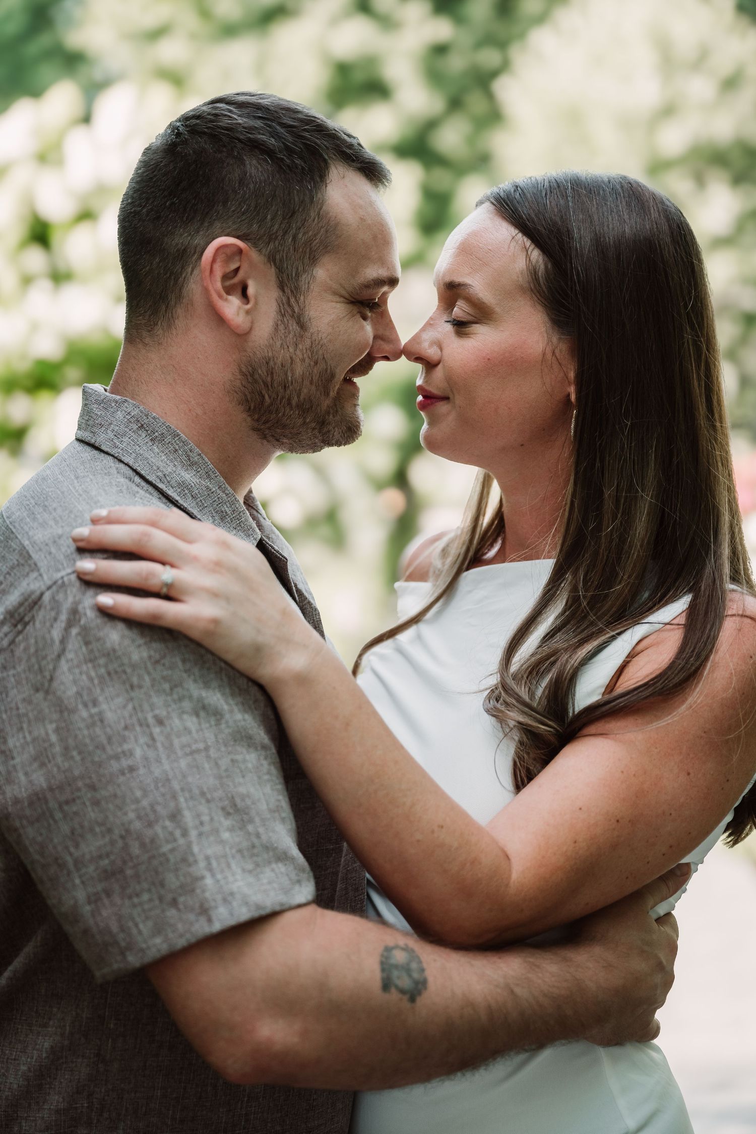 A tender moment between a couple in casual attire during an outdoor photoshoot.