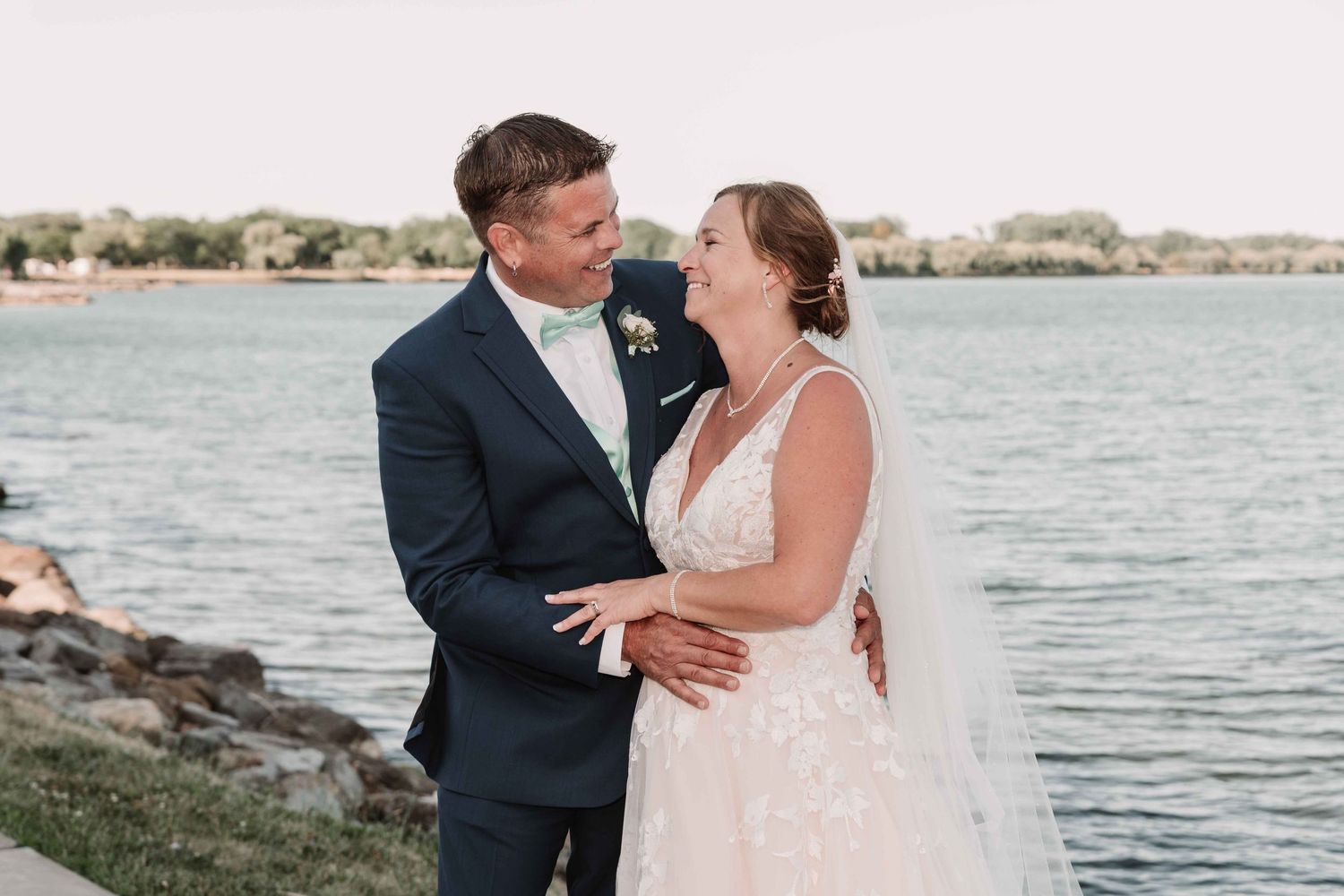 Couple embraces during their waterfront wedding photoshoot at sunset.