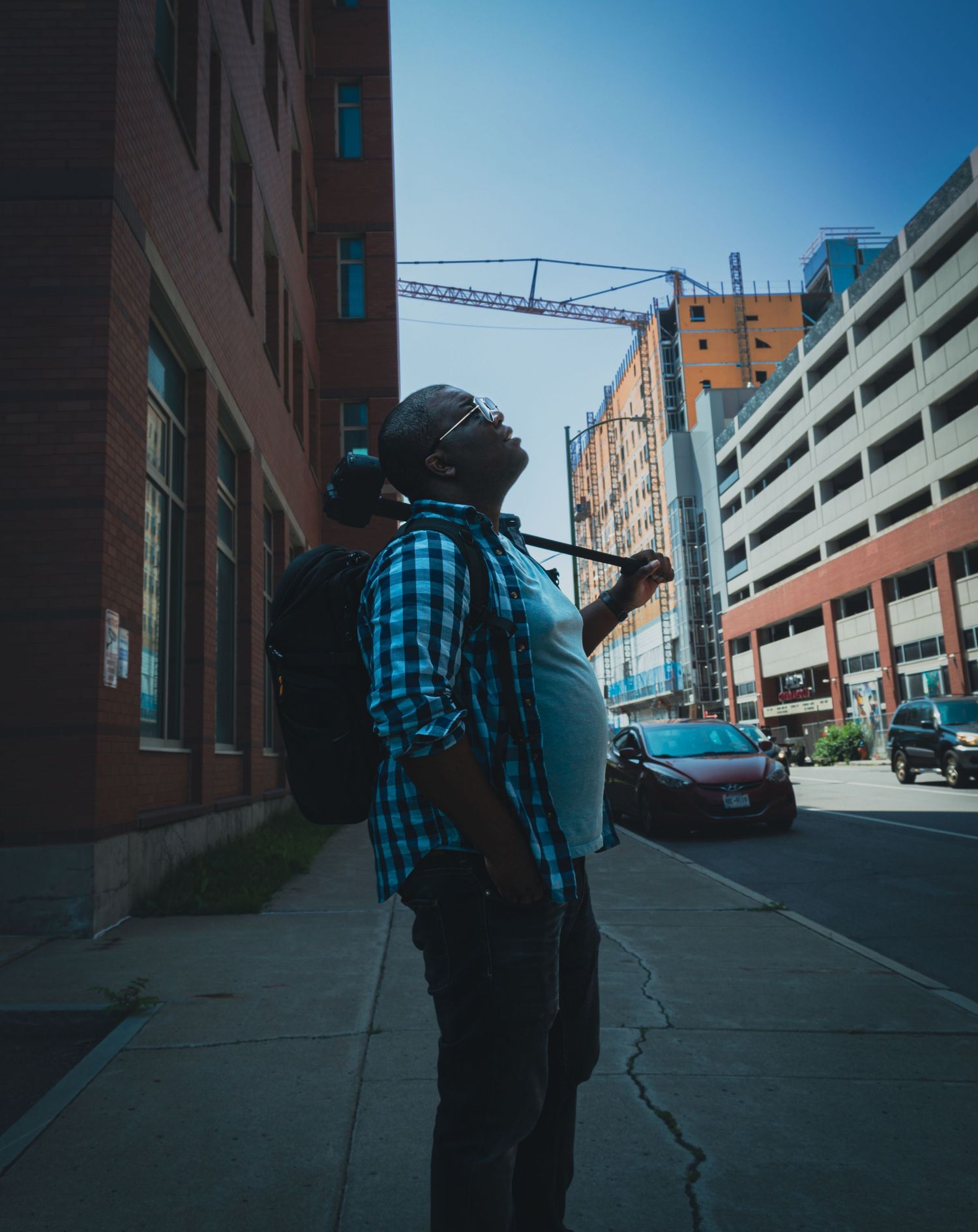 Person in plaid shirt photographing urban architecture against blue sky.