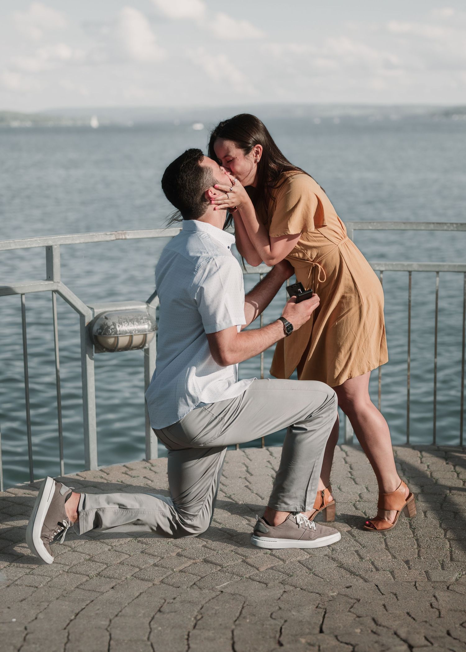 A seaside proposal scene with a couple sharing an emotional moment by the water.
