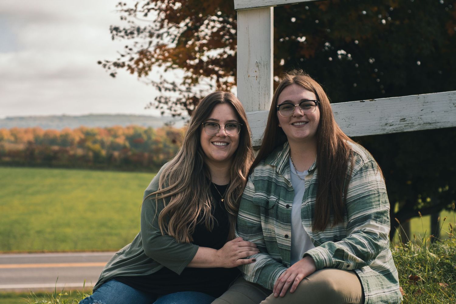 Candid engagement photos of couple relaxing by rustic fence.