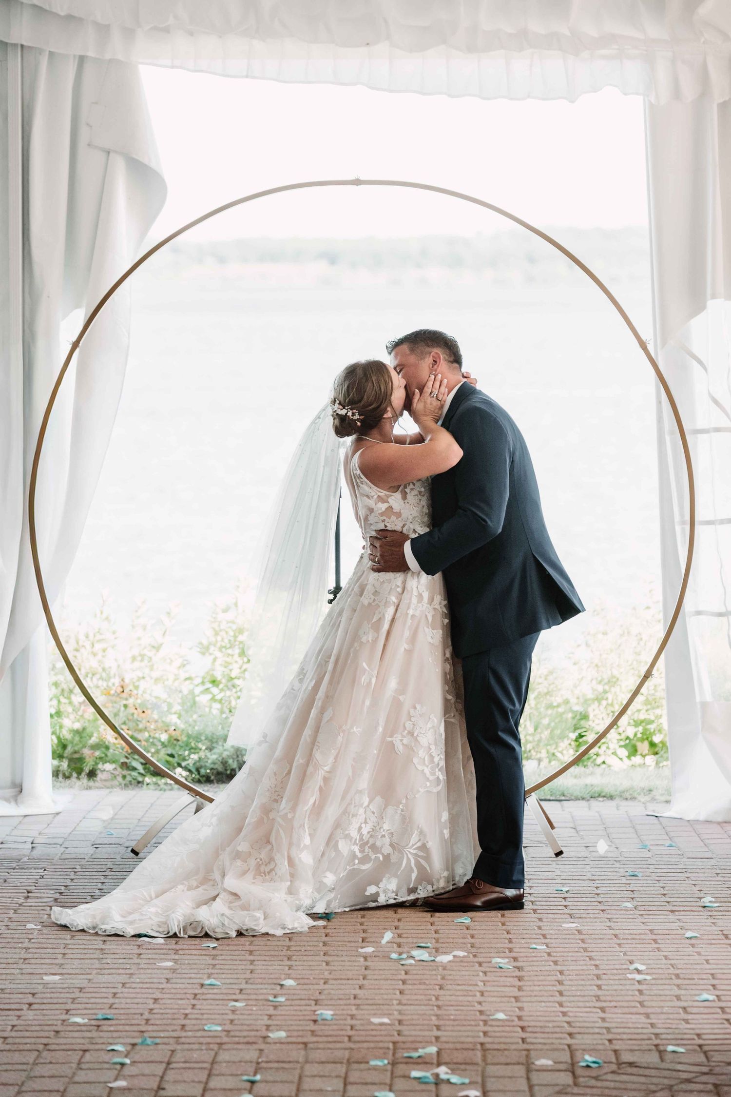 Wedding couple poses under decorative arches in a light-filled venue.