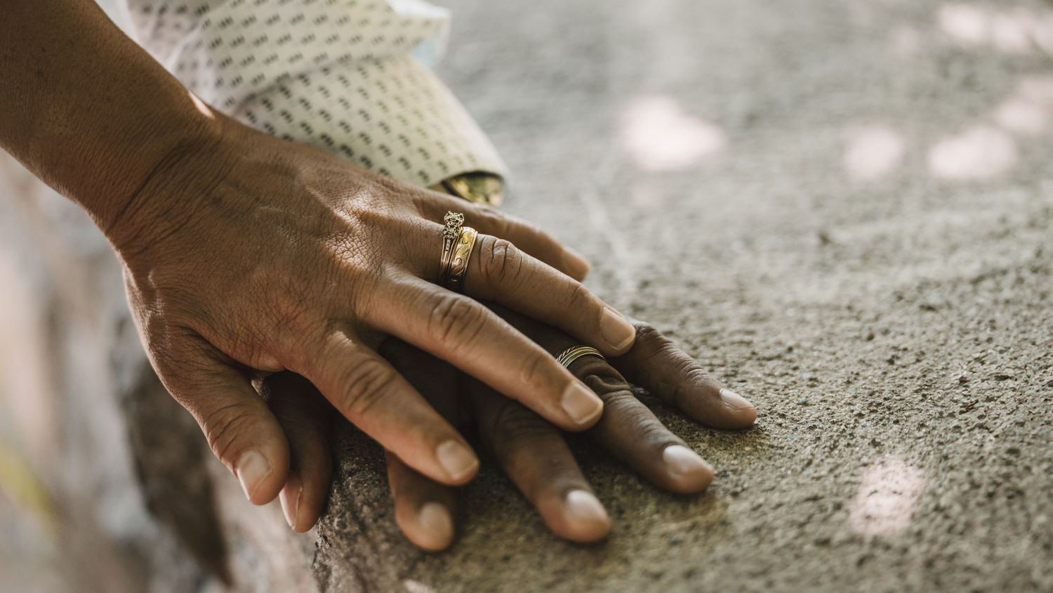 Detail shots of hands with wedding rings on textured surface.