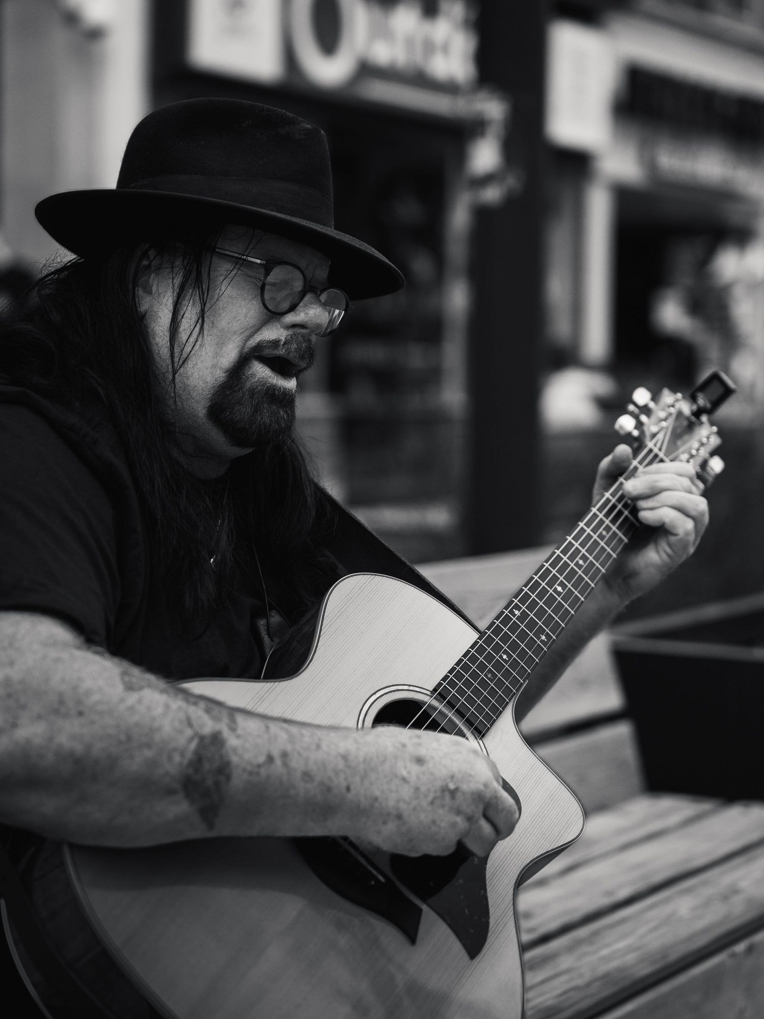 Musician playing acoustic guitar in black and white street photography.