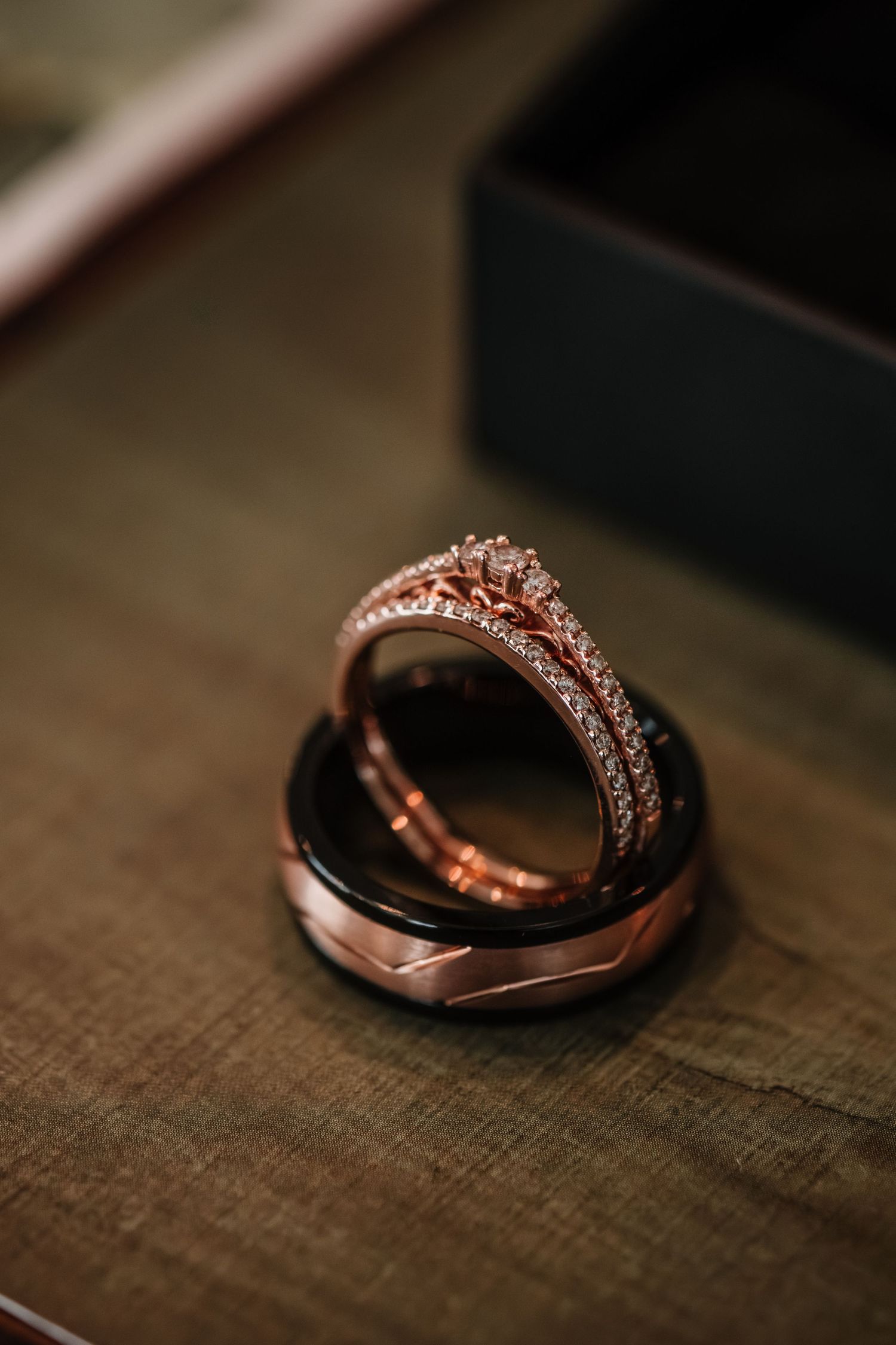Rose gold wedding rings with diamond details on wooden surface.