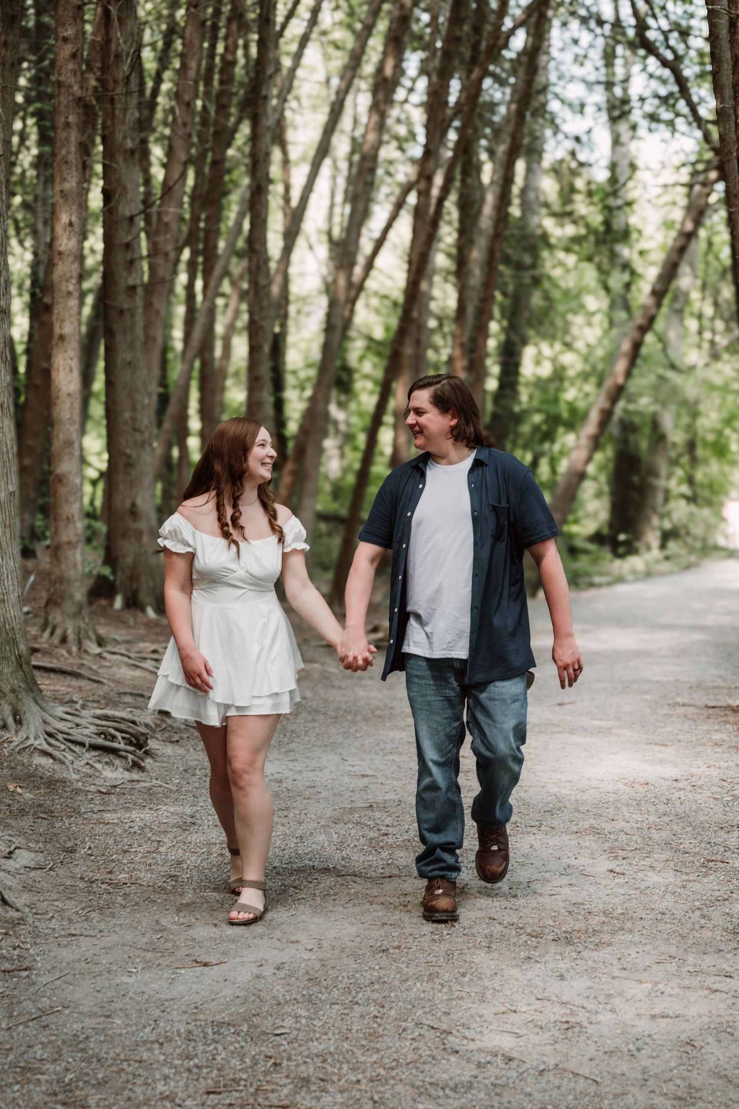Couple walking hand in hand along a scenic wooded path.
