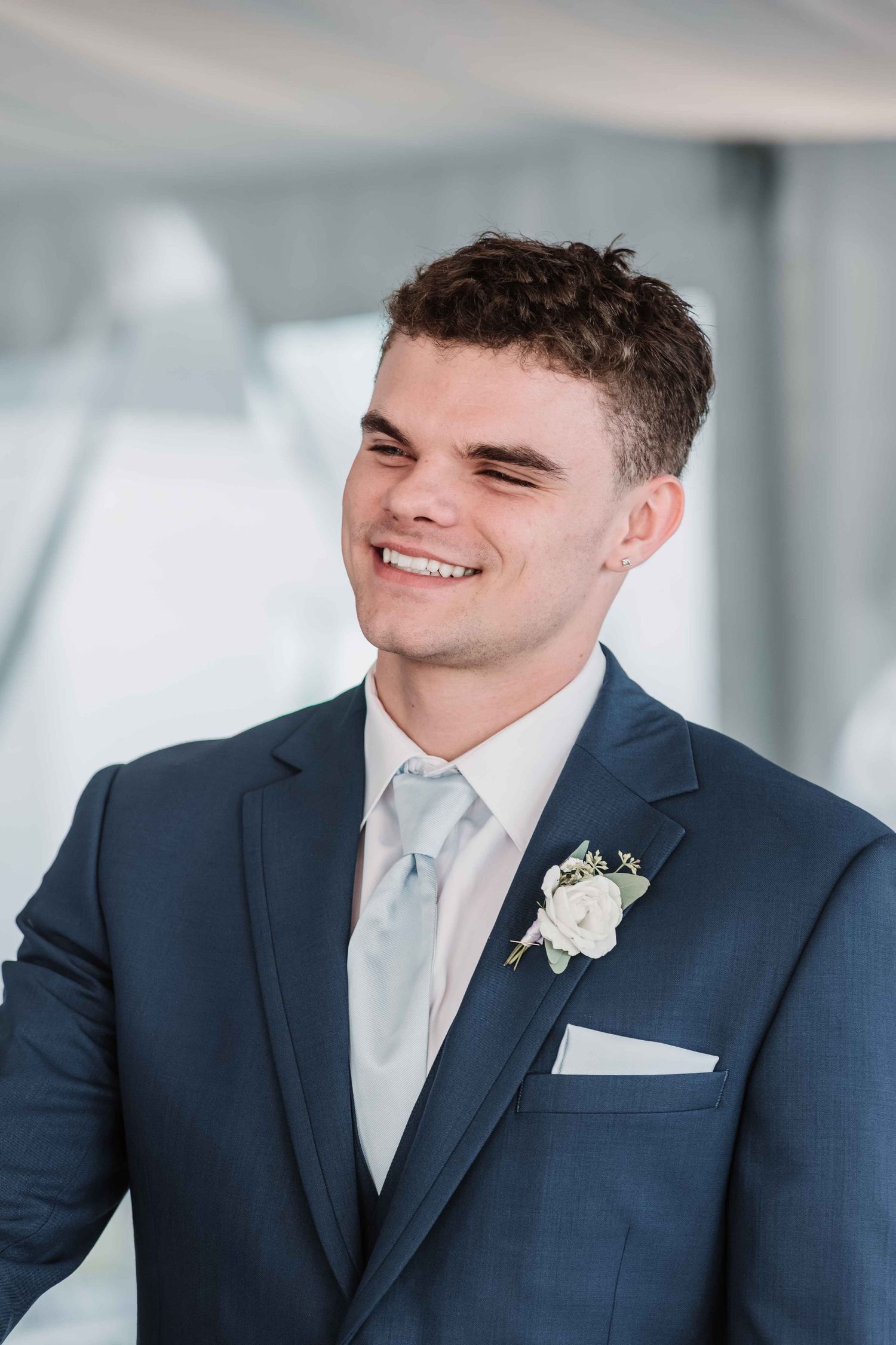Groom in navy suit smiles warmly in sequence of wedding portraits.