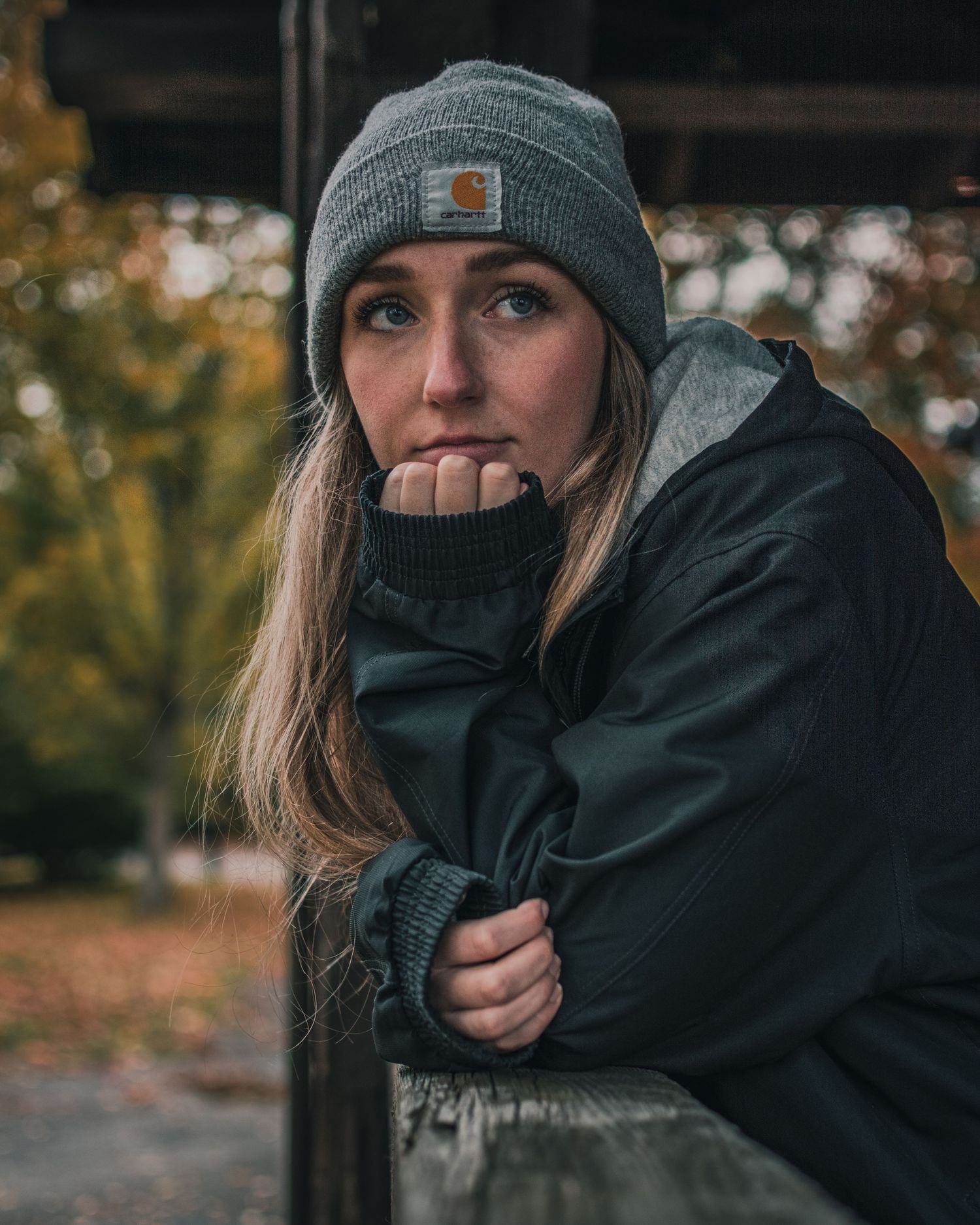 Winter portrait series featuring someone in a beanie and black jacket against an autumn background.