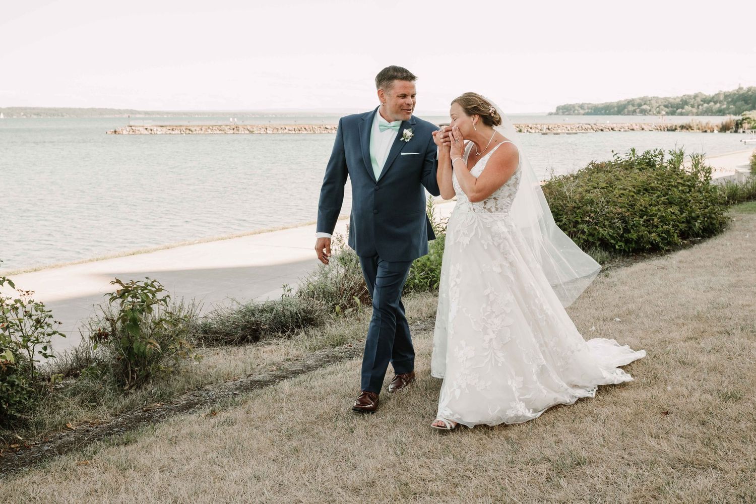 Wedding couple walks along scenic coastal path during sunset photoshoot.