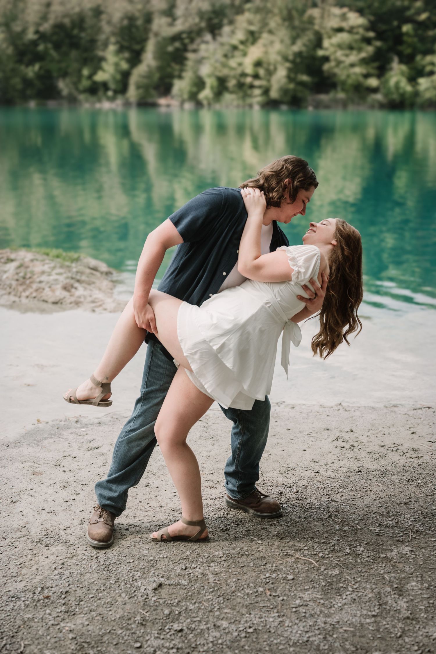 A romantic dance sequence by a turquoise lake shows a couple in white and dark clothing.