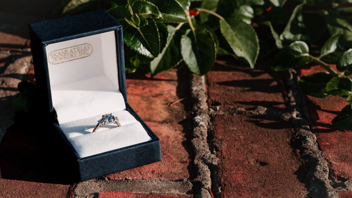 Engagement ring box displayed on textured brown surface.