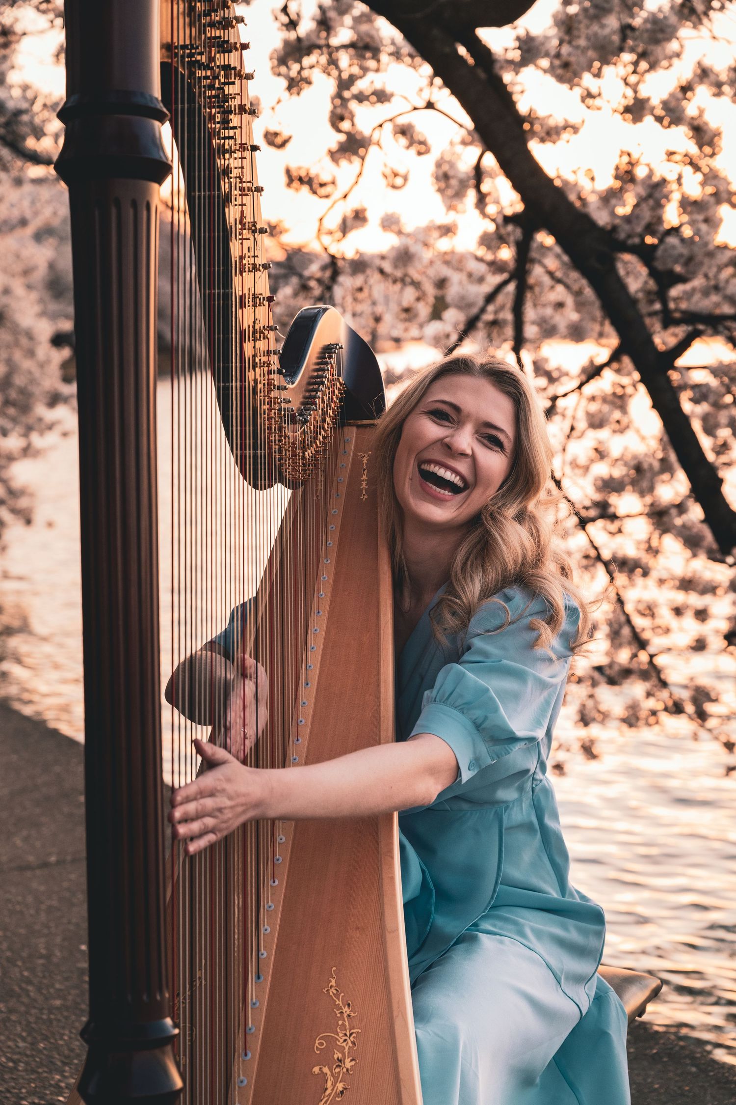 Joyful moments captured with a harp player in a blue dress among cherry blossoms at sunset.