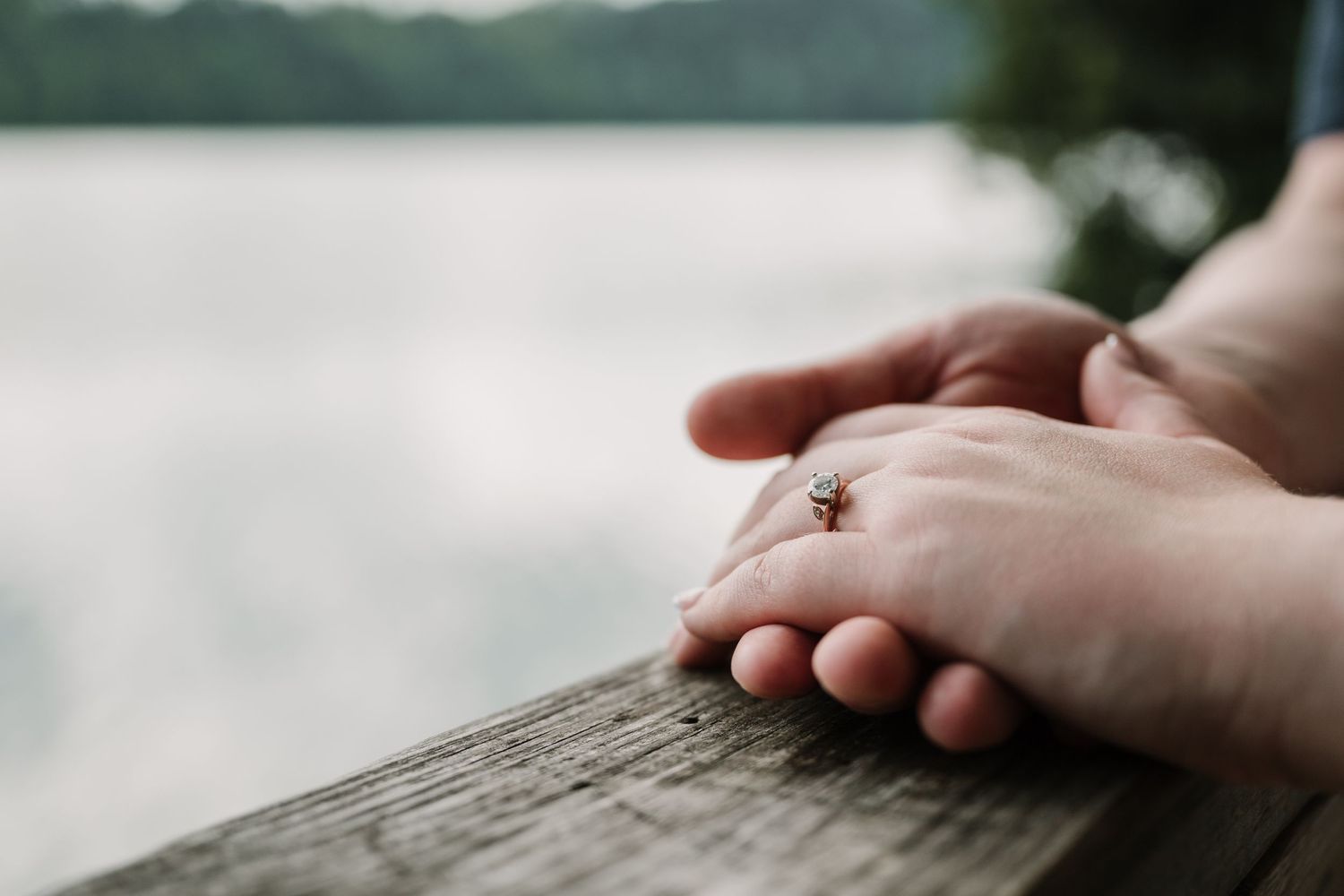 A couple embraces in a romantic outdoor photoshoot with soft natural lighting and greenery in the background.