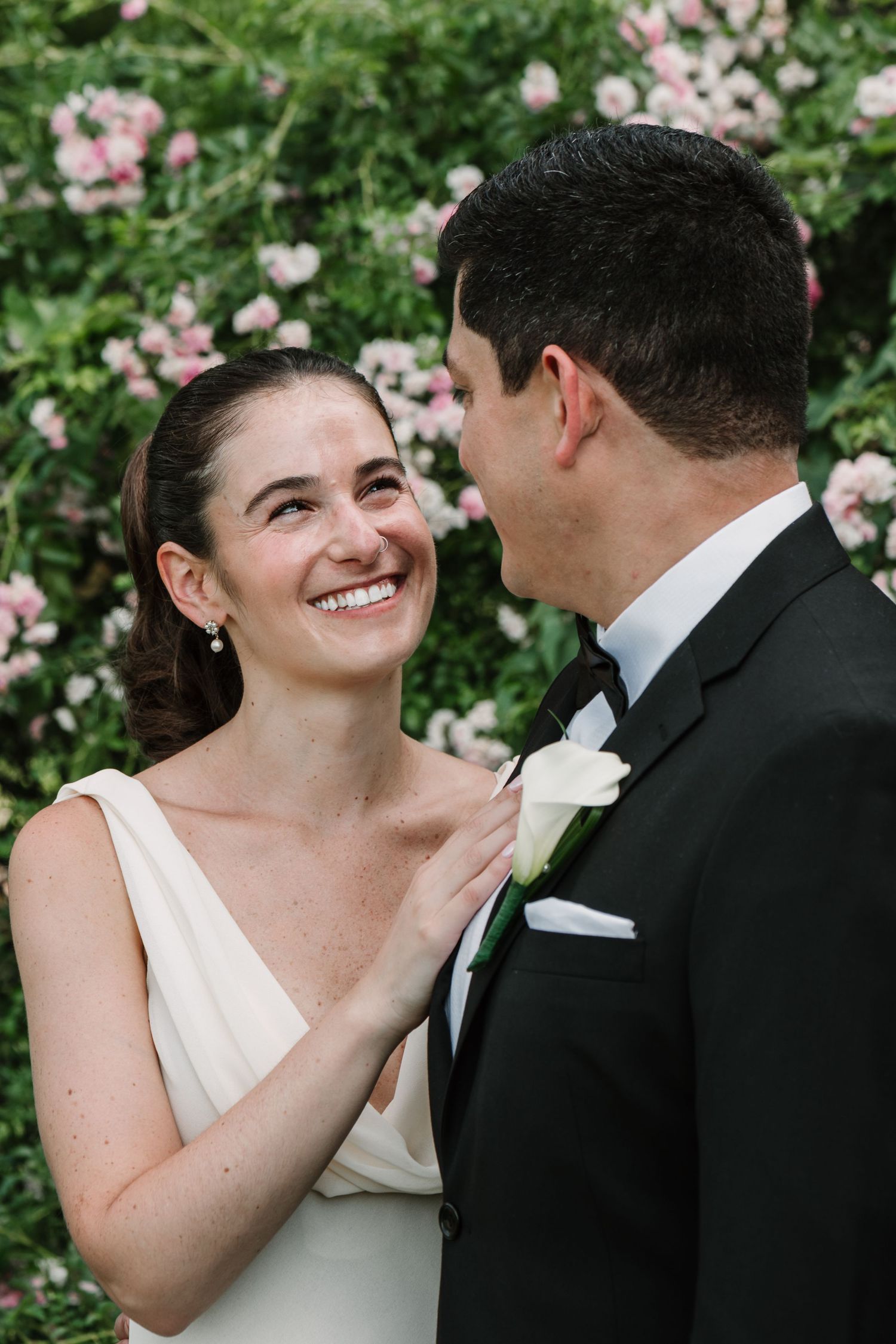 A tender wedding moment captured in front of blooming pink roses.