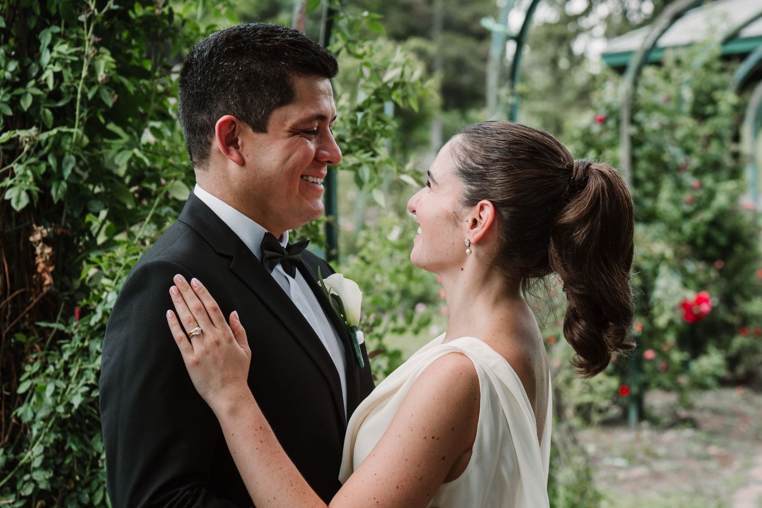 A romantic moment between newlyweds in a garden setting with green foliage.