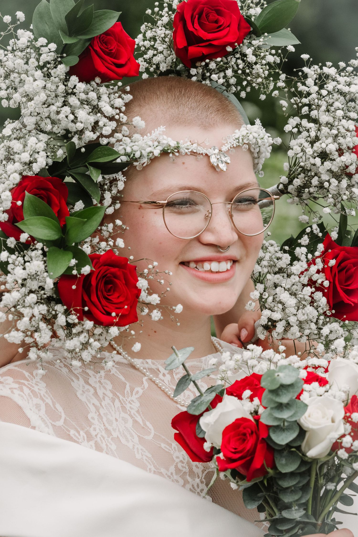 Wedding bouquet featuring vibrant red roses and delicate baby's breath flowers.