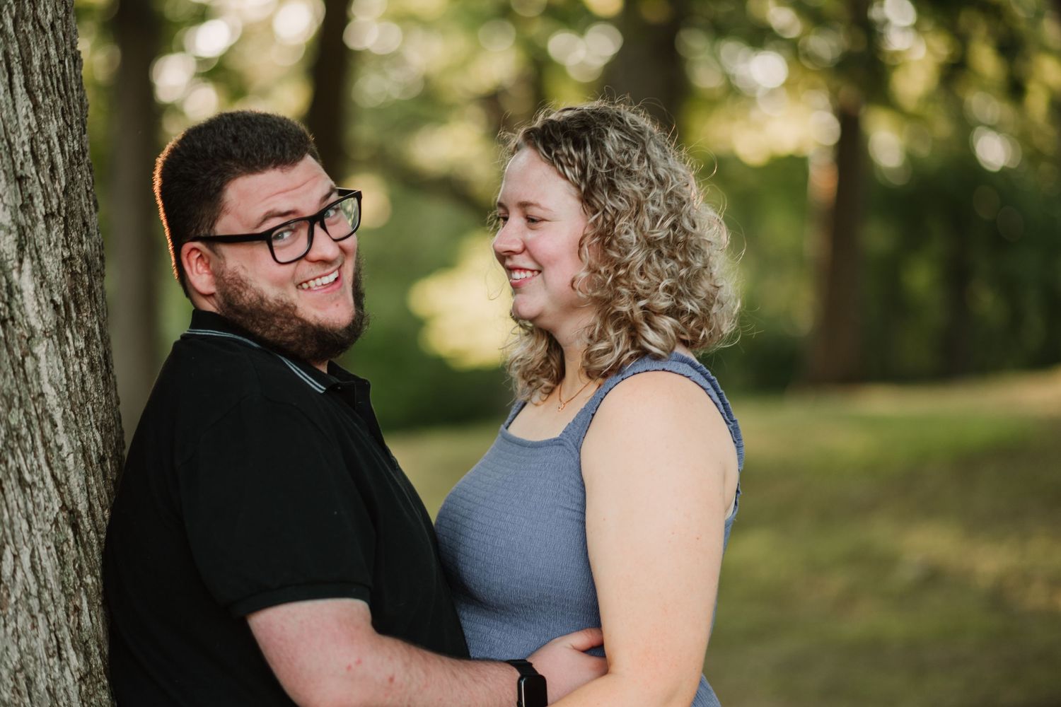 A couple shares a joyful moment together in a wooded park setting.