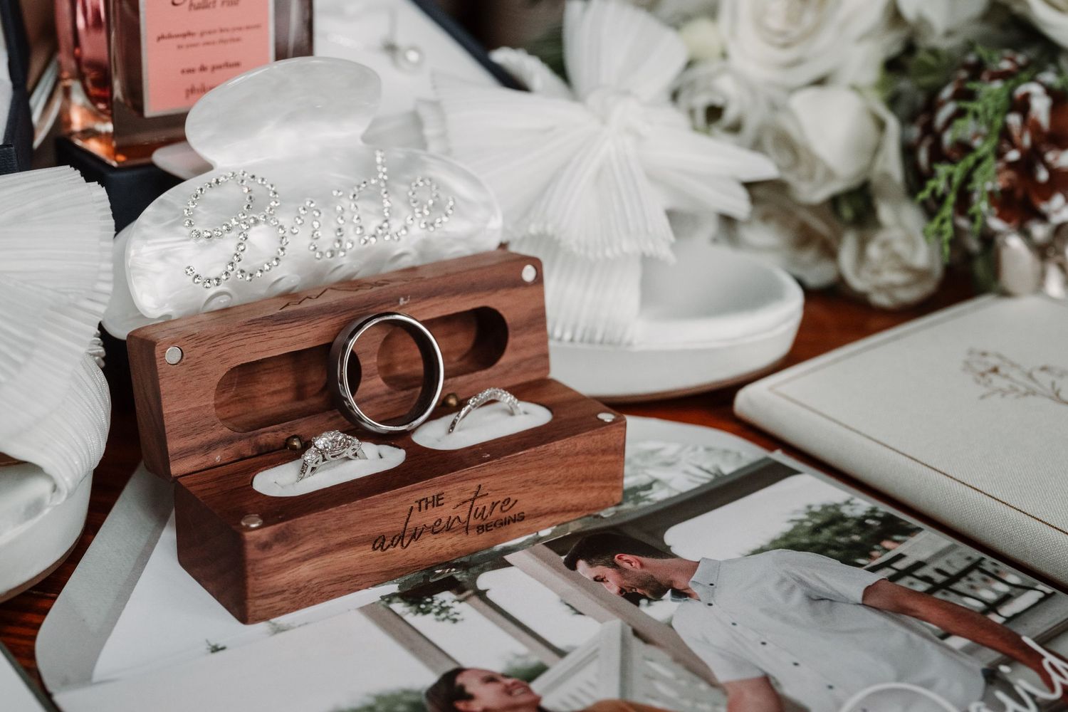 Wedding rings and decorative details arranged on wooden boxes with white floral accents.