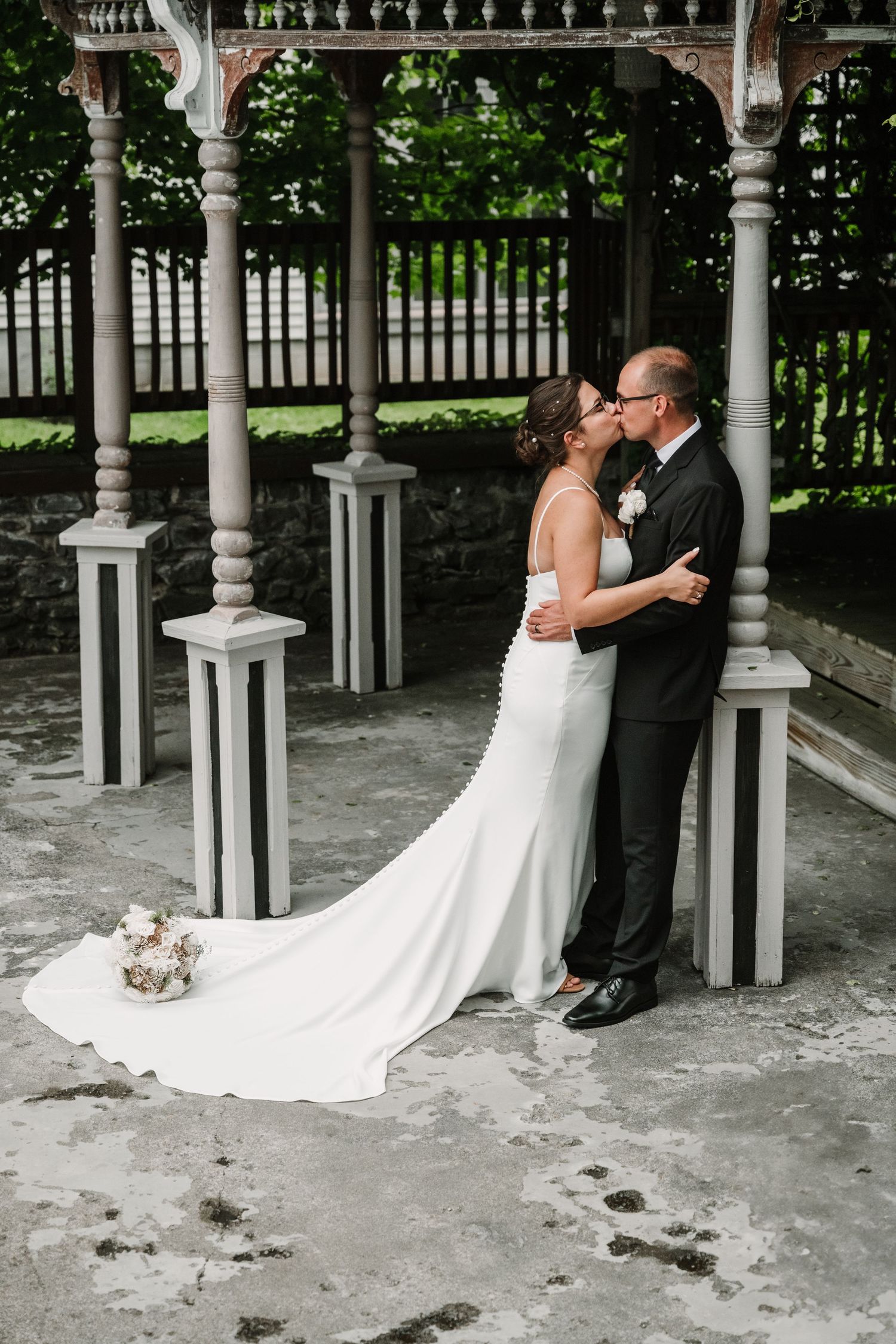 Wedding portraits taken under an elegant white gazebo with ornate pillars.