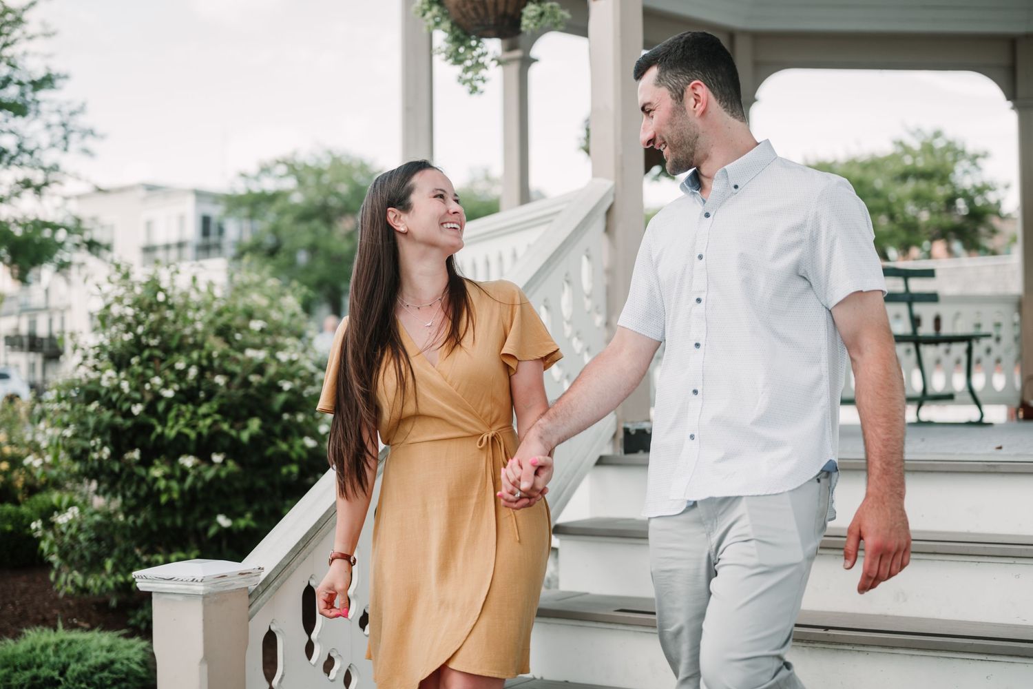 Romantic couple in casual attire sharing a moment on a white porch.