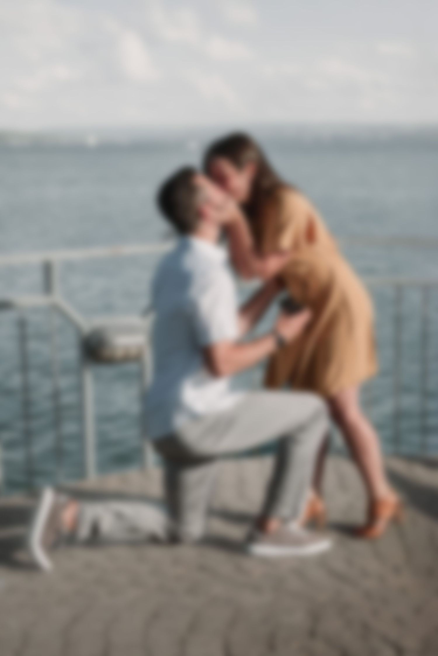 A romantic proposal moment unfolds on a seaside pier with ocean views.