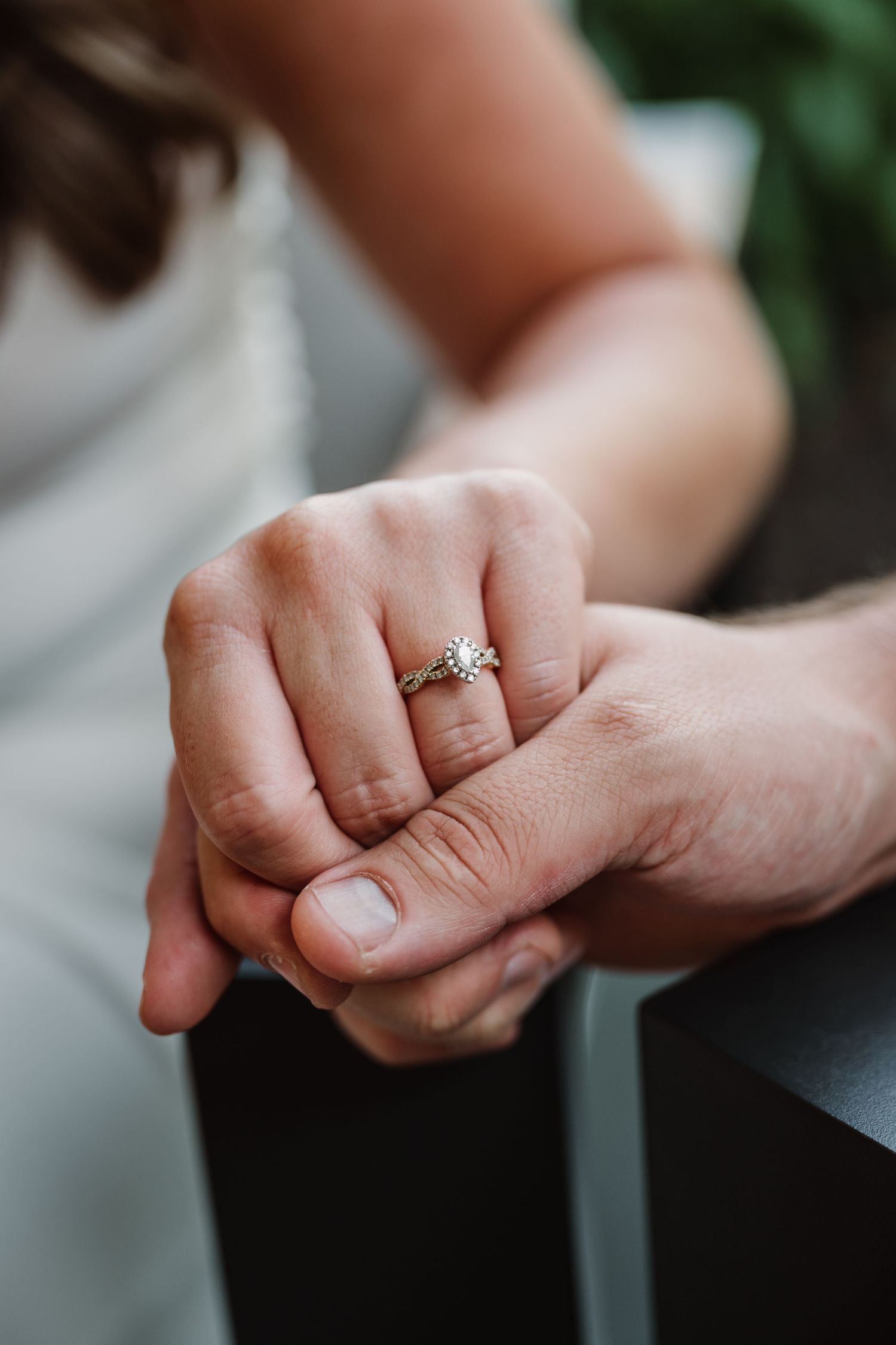 Close-up of hands with an engagement ring showing a tender moment between a couple.
